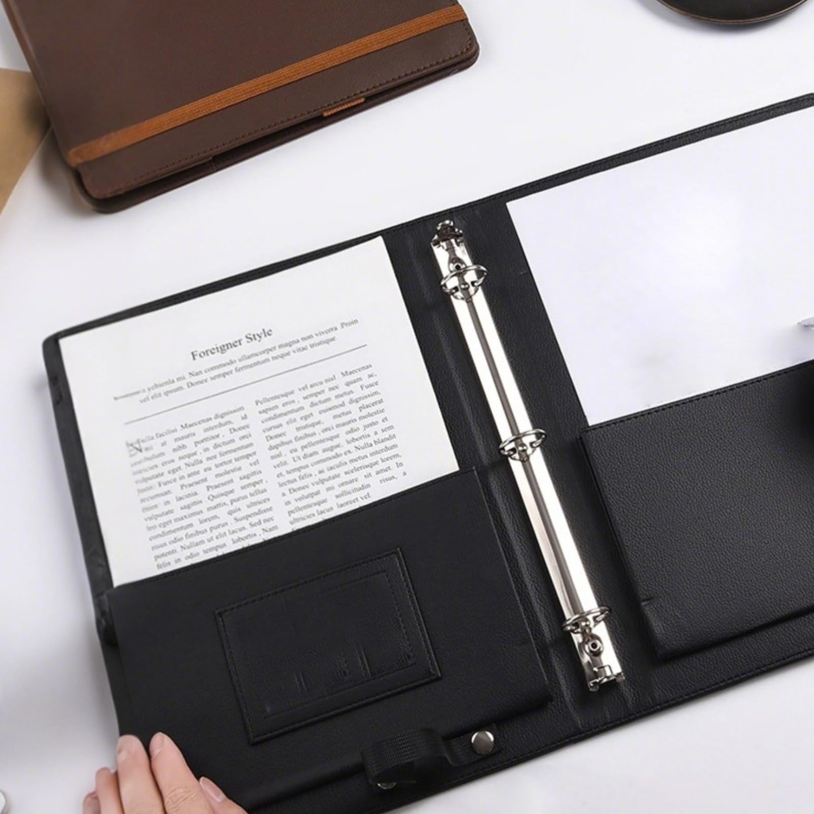 Raccoglitore A4 in pelle nera a tre anelli con design multitasche e chiusura elastica, pratico per appunti, contratti e documenti