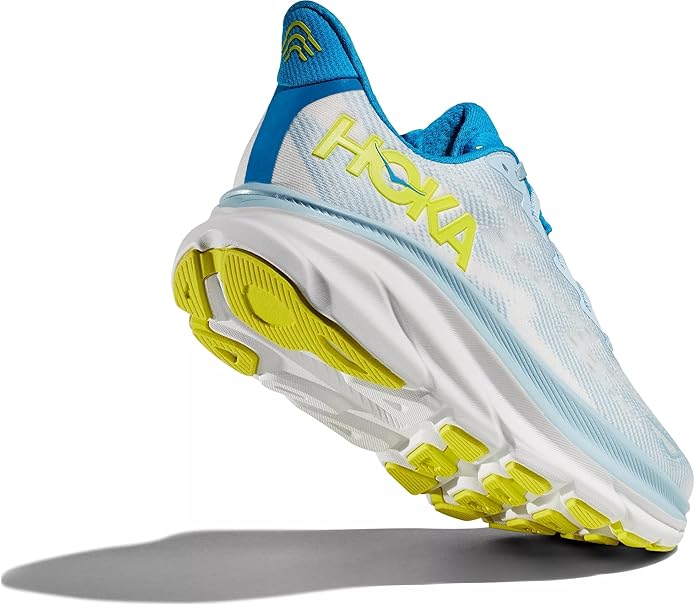  A single HOKA Men’s Clifton 9 Running Shoe in blue and white, featuring a yellow sole and the HOKA logo in yellow on the side. The shoe is angled to show both the side profile and the sole, casting a shadow on a light gray background.