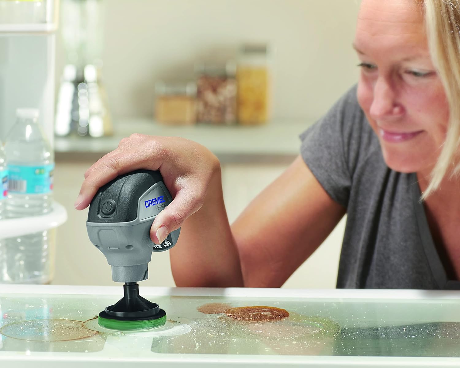 Dremel Versa cleaning a refrigerator shelf with a green pad