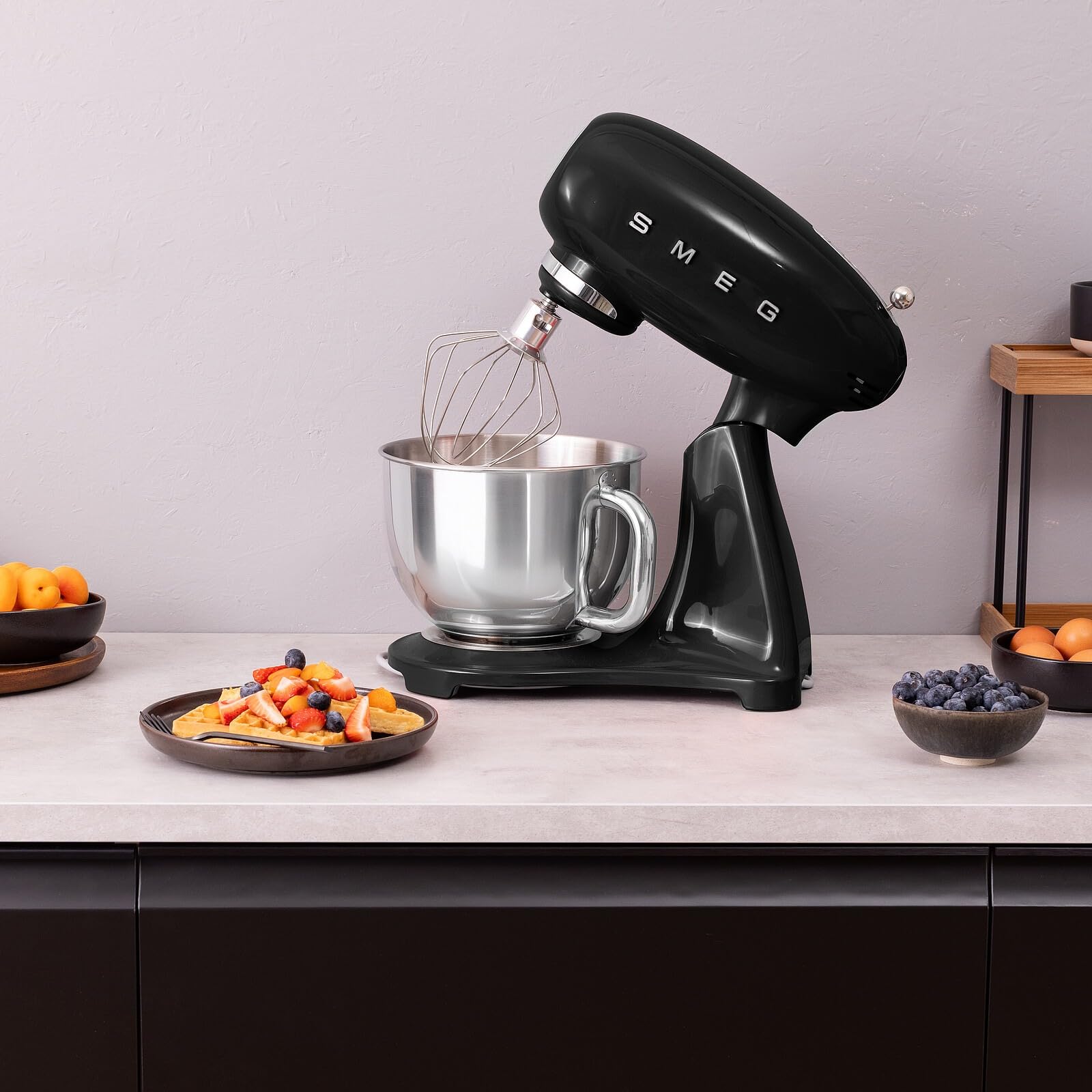 SMEG SMF05 Forte Stand Mixer in black with the wire whisk attachment in the stainless steel bowl.