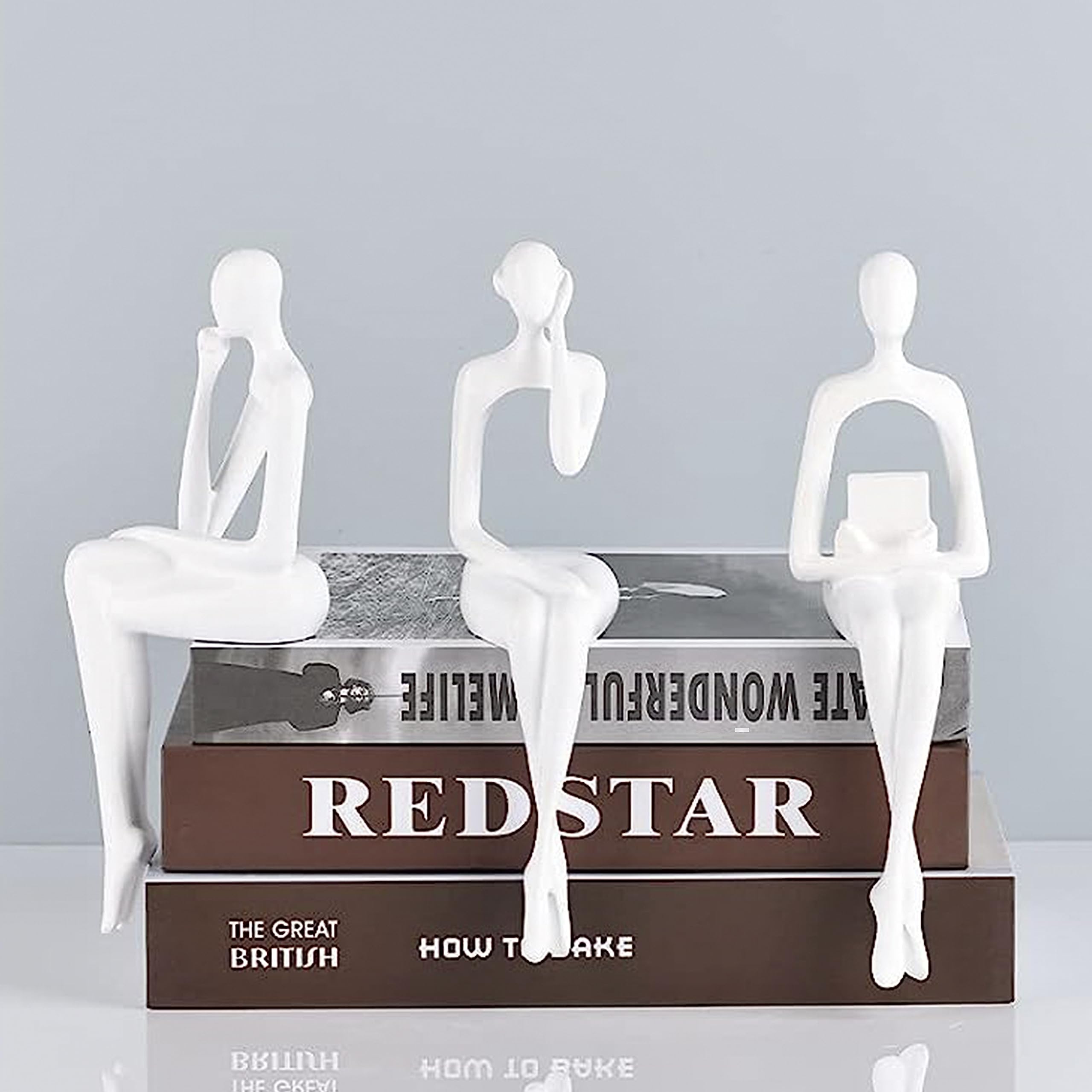 Statua seduta, una scultura astratta di una persona seduta su una libreria pensando