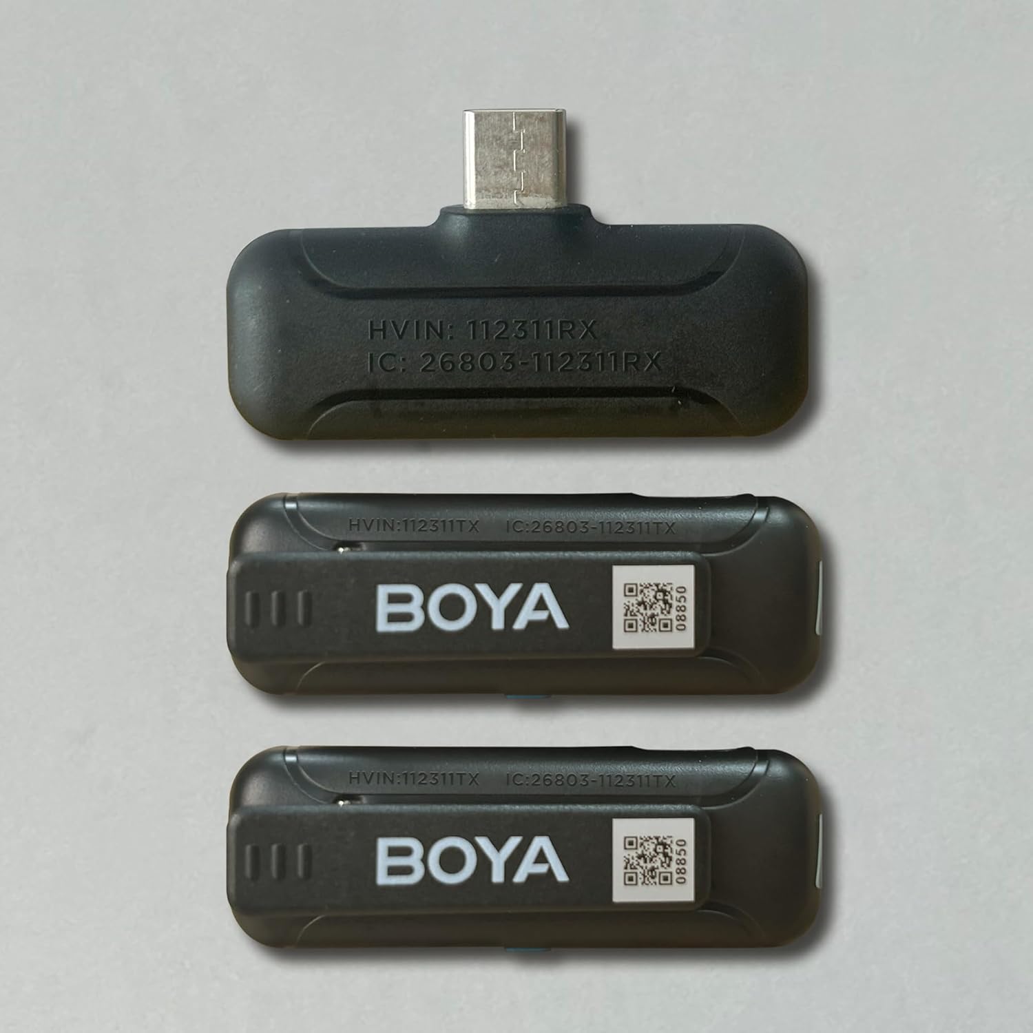 Detailed diagram of the BOYA BY-WM3T-RXD receiver and BY-WM3T-TX transmitter, highlighting the USB-C connector, charging contacts, USB-C charging port, built-in microphone, status indicator, NR button, and power button.