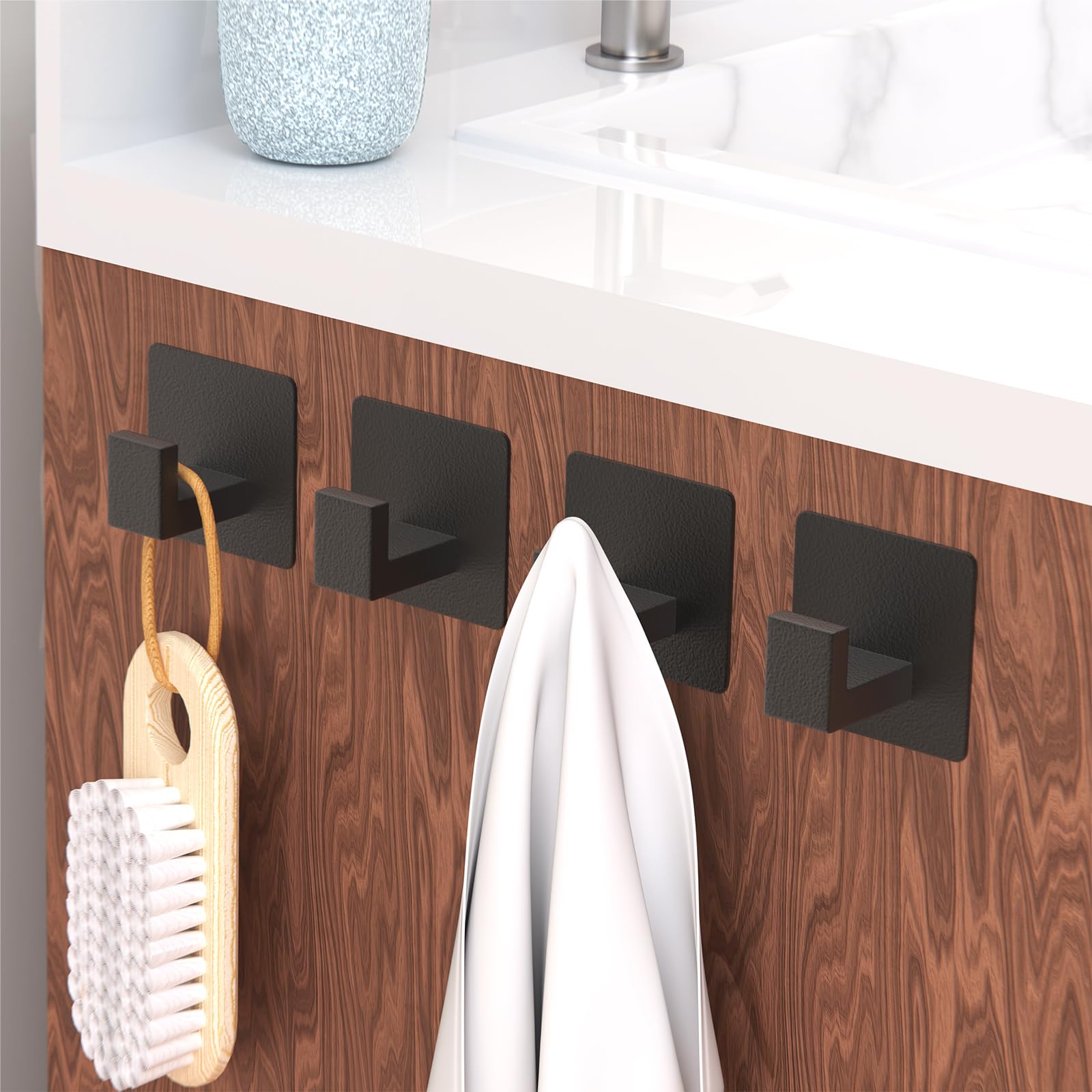 A close-up of the PMMASTO L-shape adhesive hooks, showcasing their matte black finish and compact form factor.