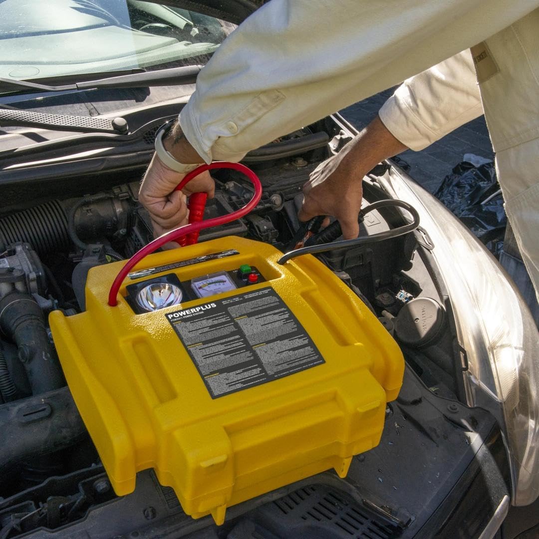 A person connecting the red jump starter clamp to a car battery's positive terminal, with the Powerstation placed on the engine bay.