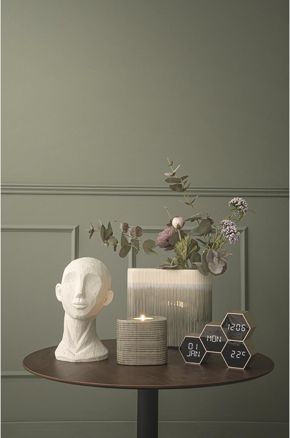 Lifestyle image of the Karlsson KA5805GD alarm clock on a wooden table next to a vase and a candle.