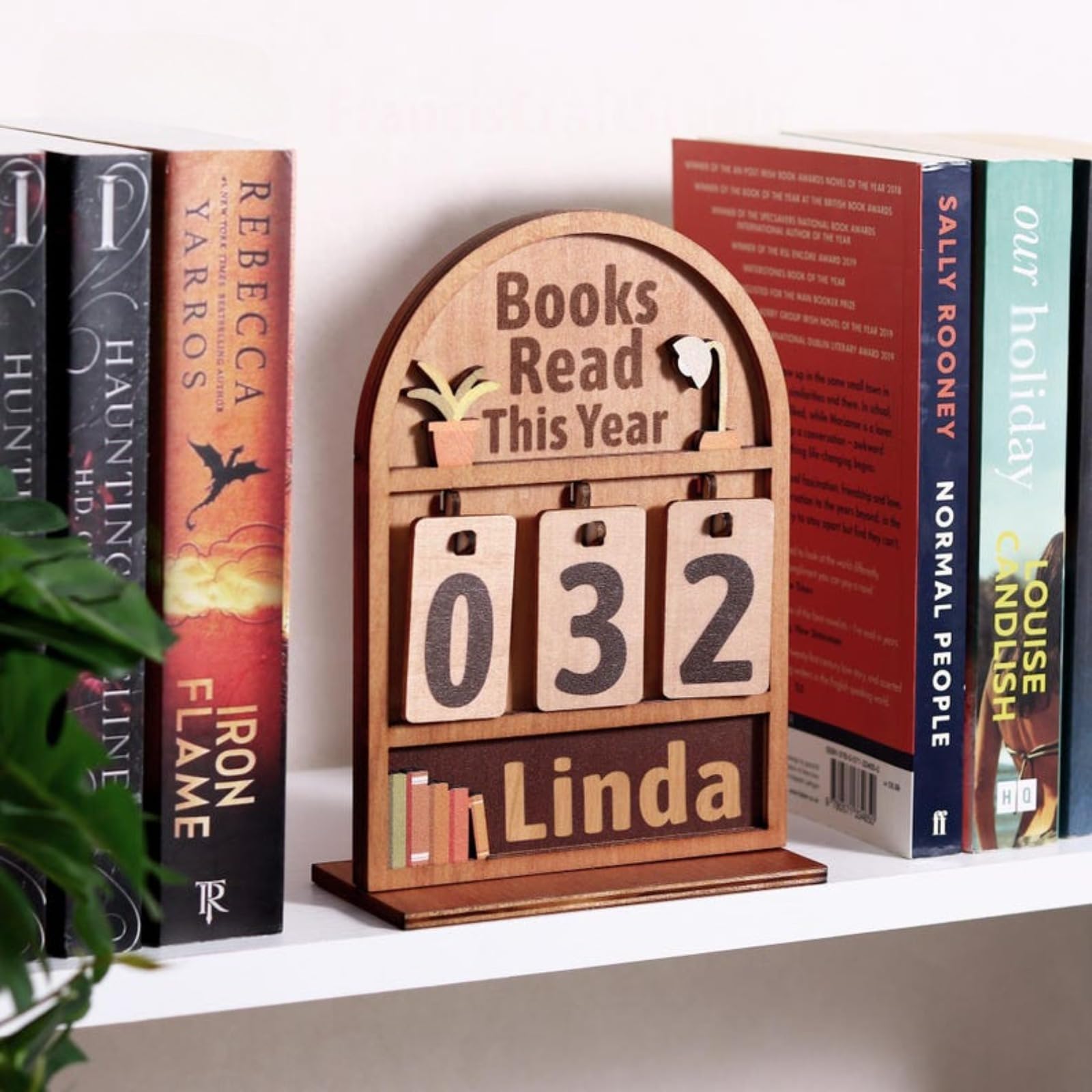 Wooden reading tracker plaque with swappable number tiles on a shelf