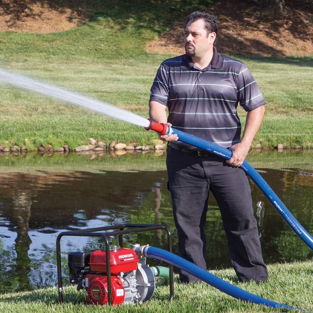 Man operating Honda WB20XT4A water pump, directing water stream