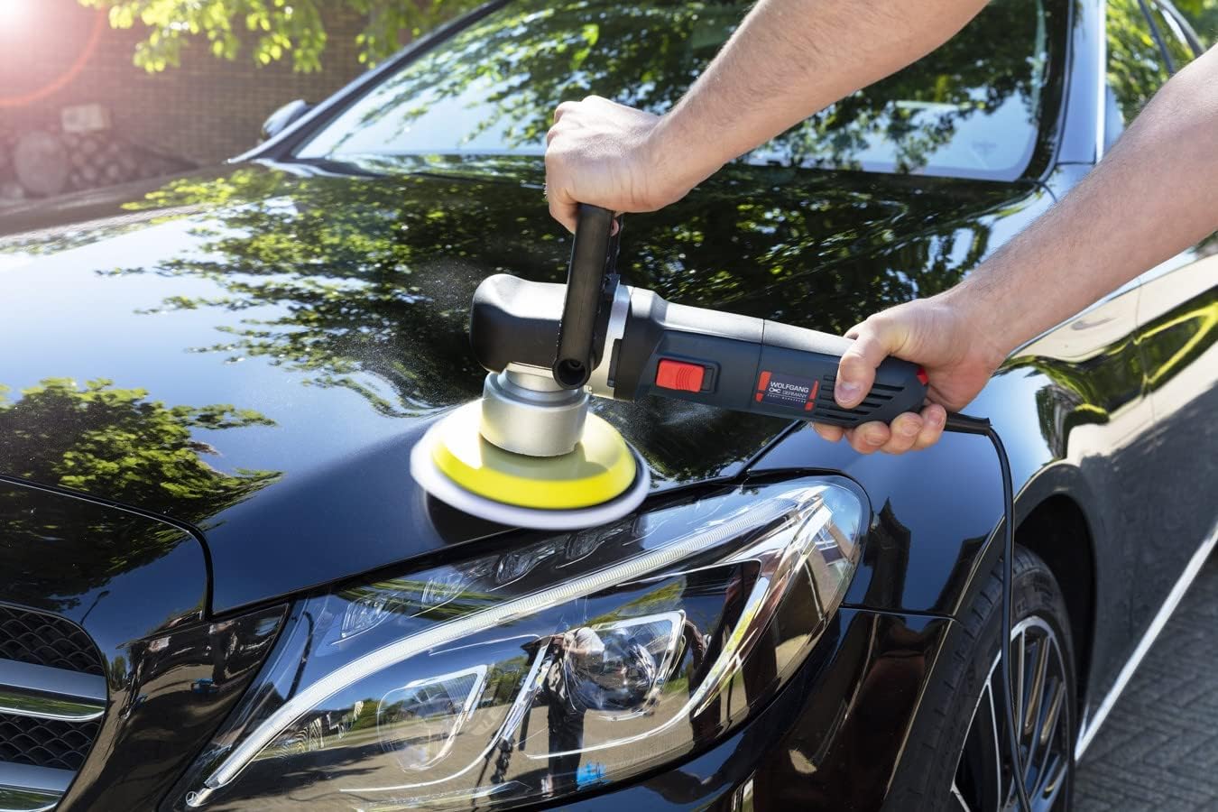 Person polishing the hood of a black car