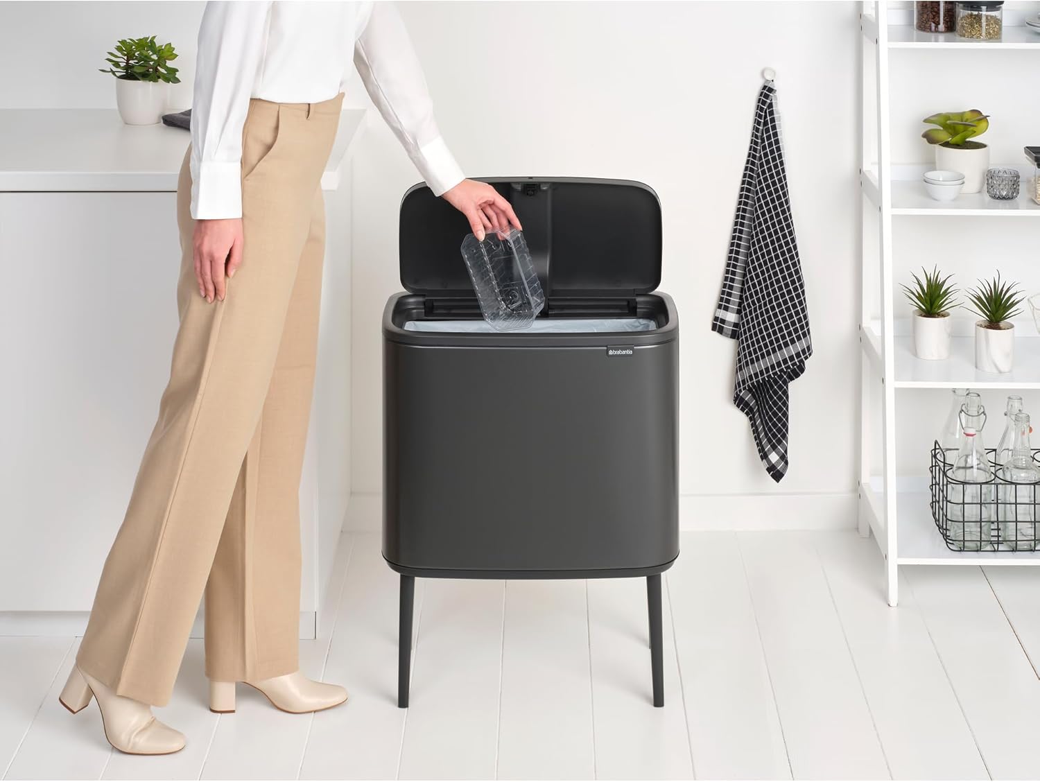 Person disposing of a plastic bottle into the open Brabantia Bo Touch Top Trash Can