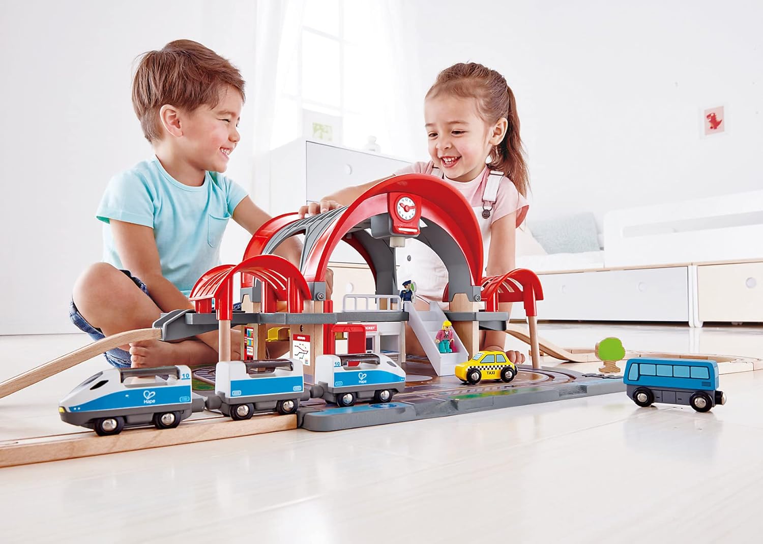 Two children happily playing with the assembled Hape Grand City Station and trains.