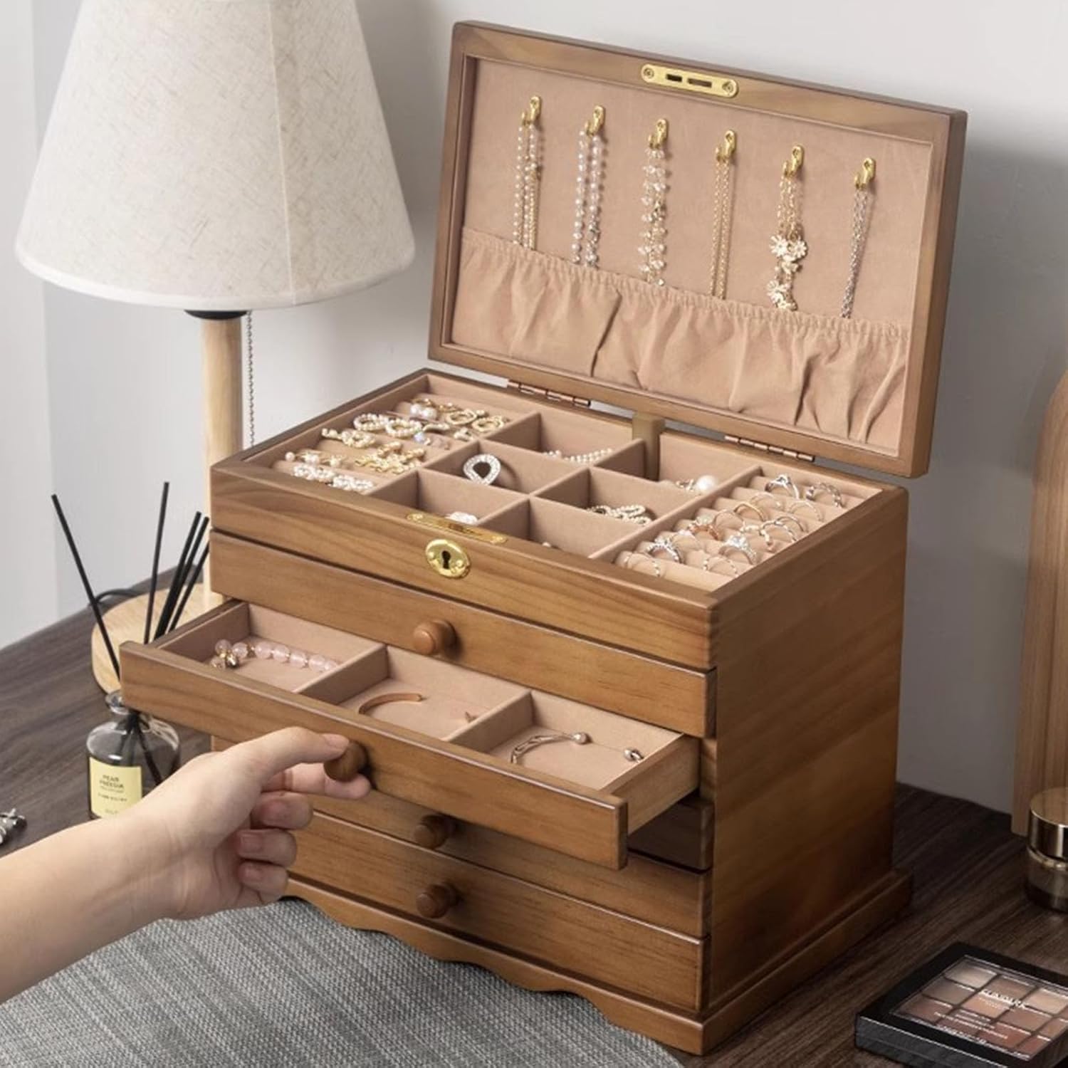 A hand pulling open one of the drawers of the TITISKIN jewelry box, revealing stored items.