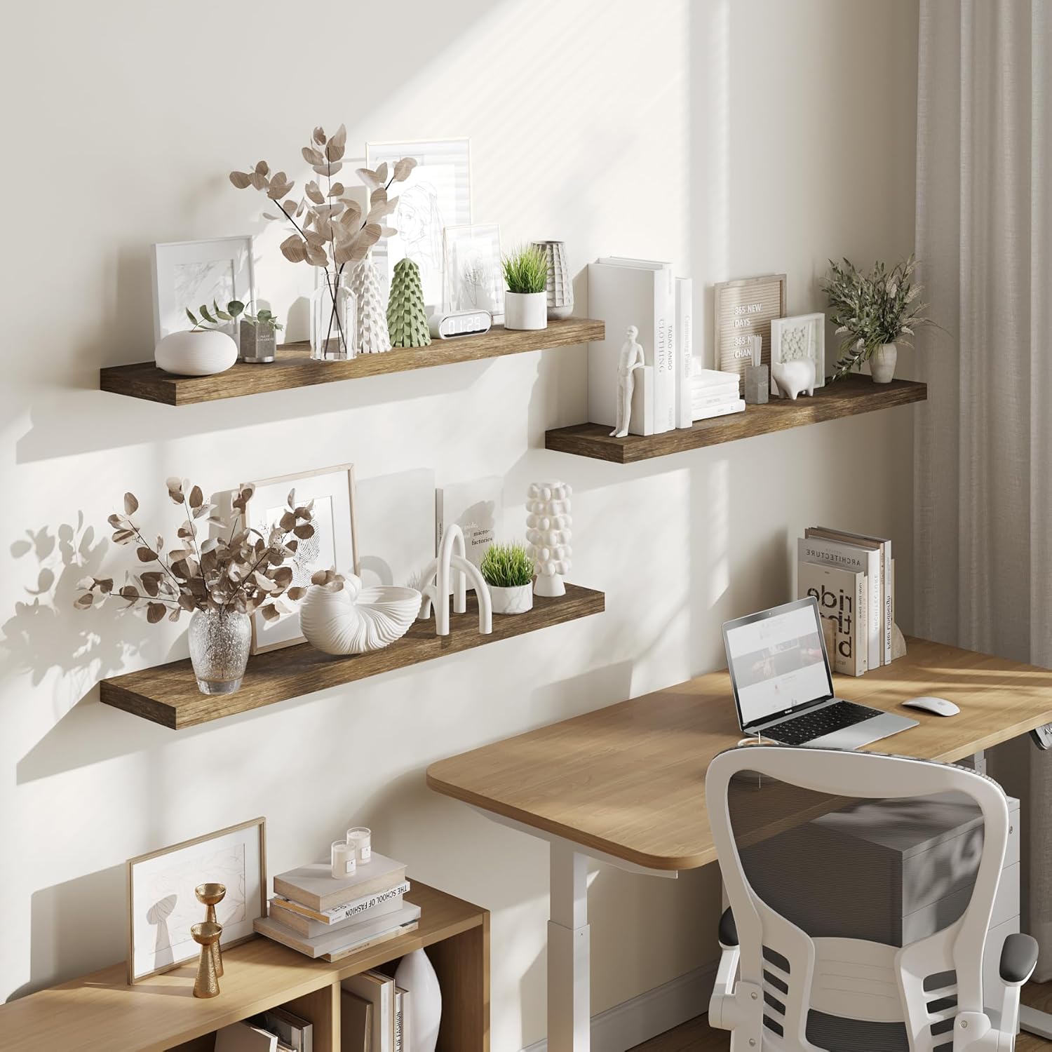 Two floating shelves installed above a desk in an office setting, holding books, plants, and decorative items.