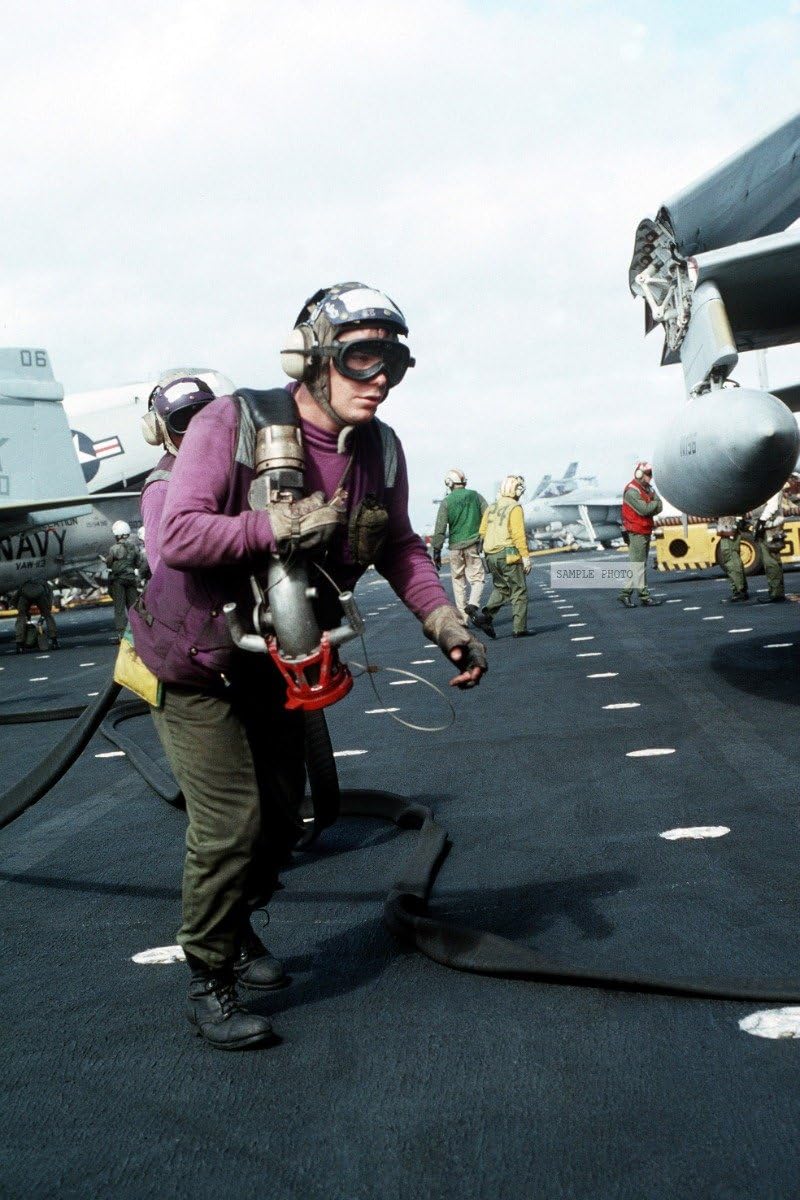 Photo An aviation fuels crew member pulls a refueling line toward an aircraft on the