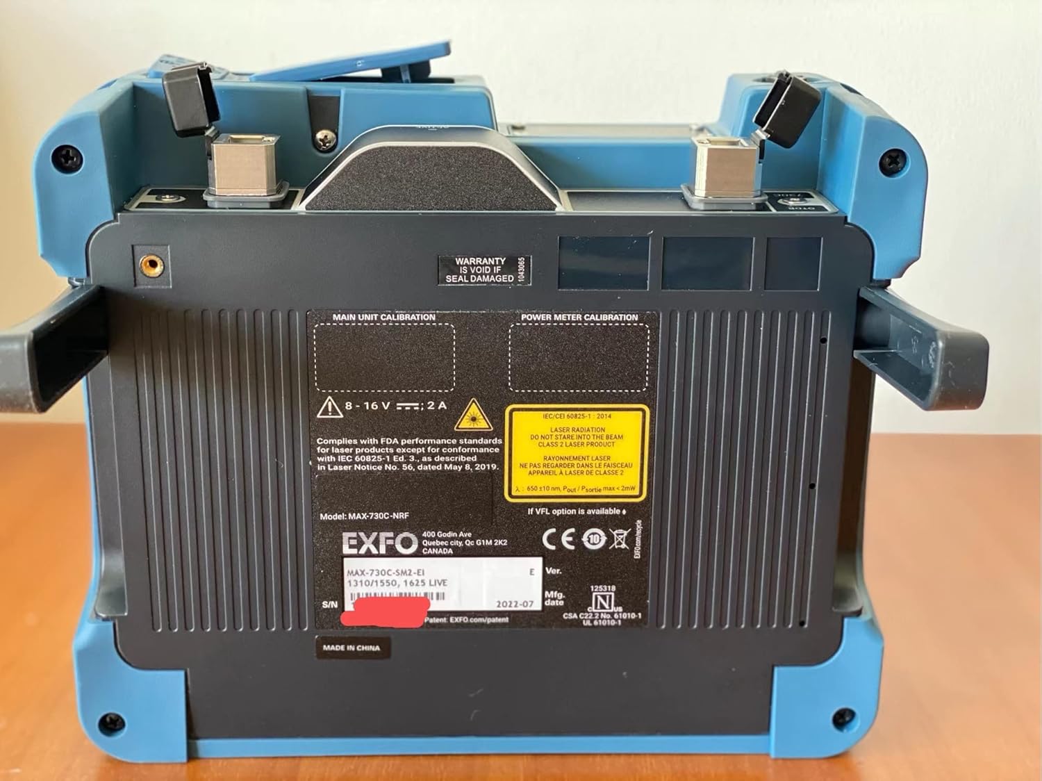 Back view of the EXFO MAX-730C OTDR showing product label with model number, serial number, and manufacturing details.