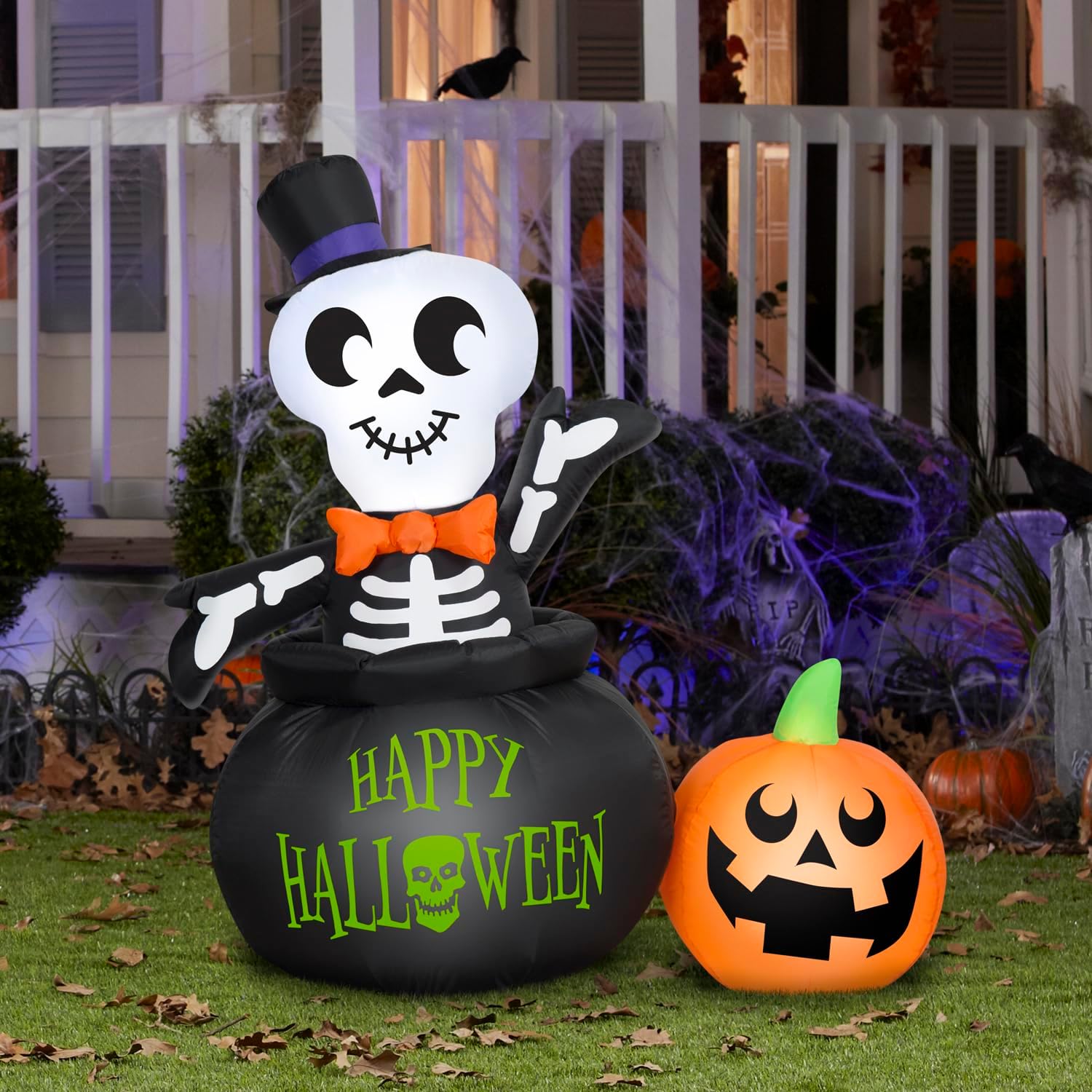 Airblown Gemmy Halloween Skeleton in Cauldron with Pumpkin inflatable displayed in an outdoor yard setting at night.