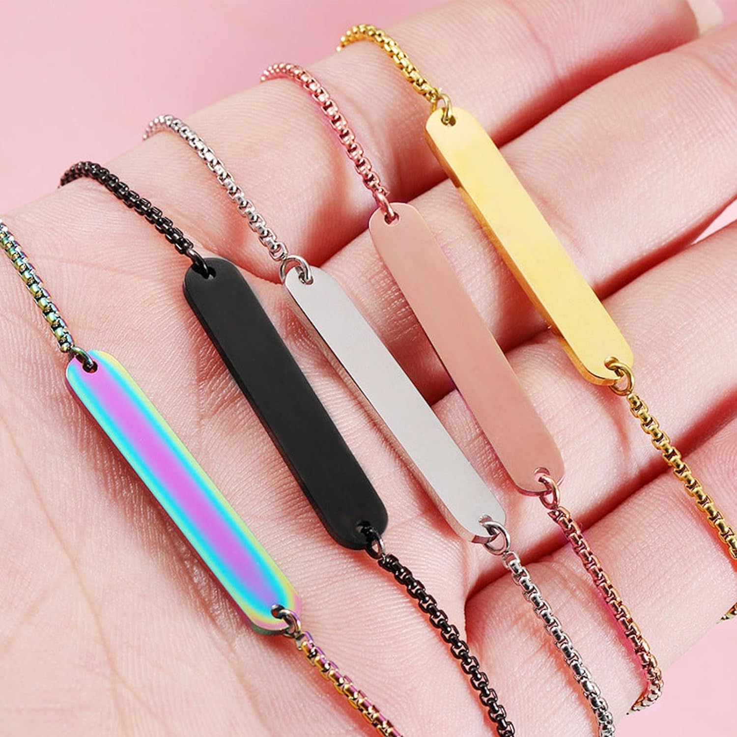 Close-up of multiple engraved bar necklaces/bracelets in various metallic colors, showcasing detailed laser engravings.