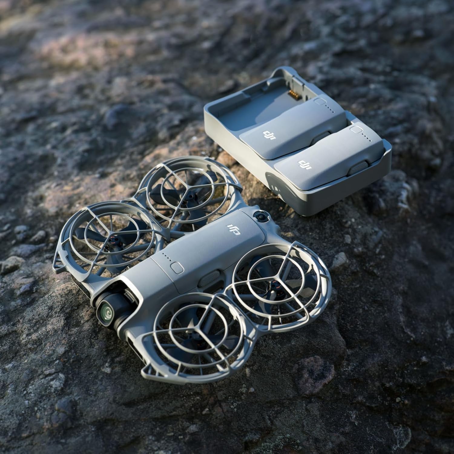 DJI Neo 2 drone and two-way charging hub on a rock surface.