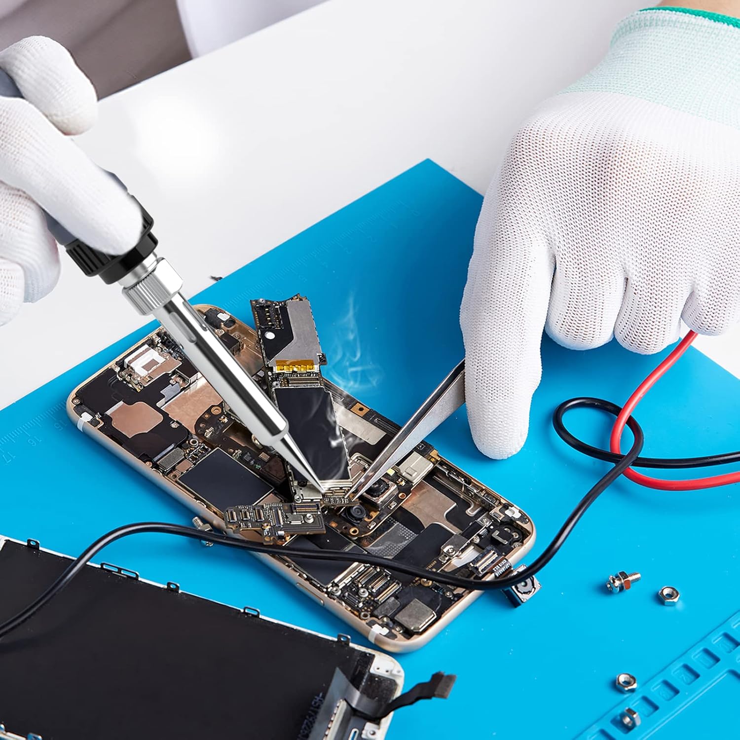 Close-up of hands using a BAKON soldering iron to repair a mobile phone component