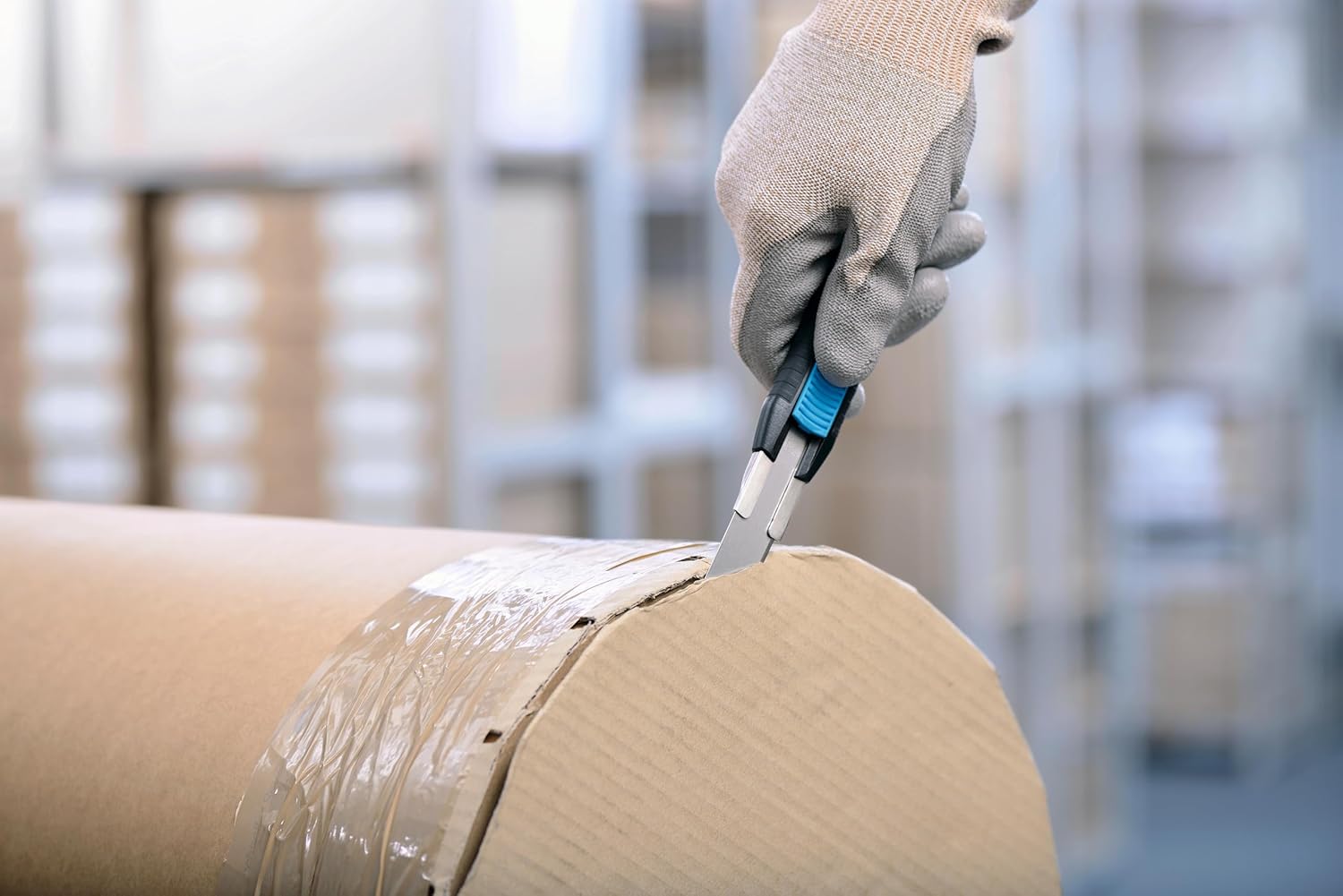 Person cutting a large roll of paper or film with the safety knife