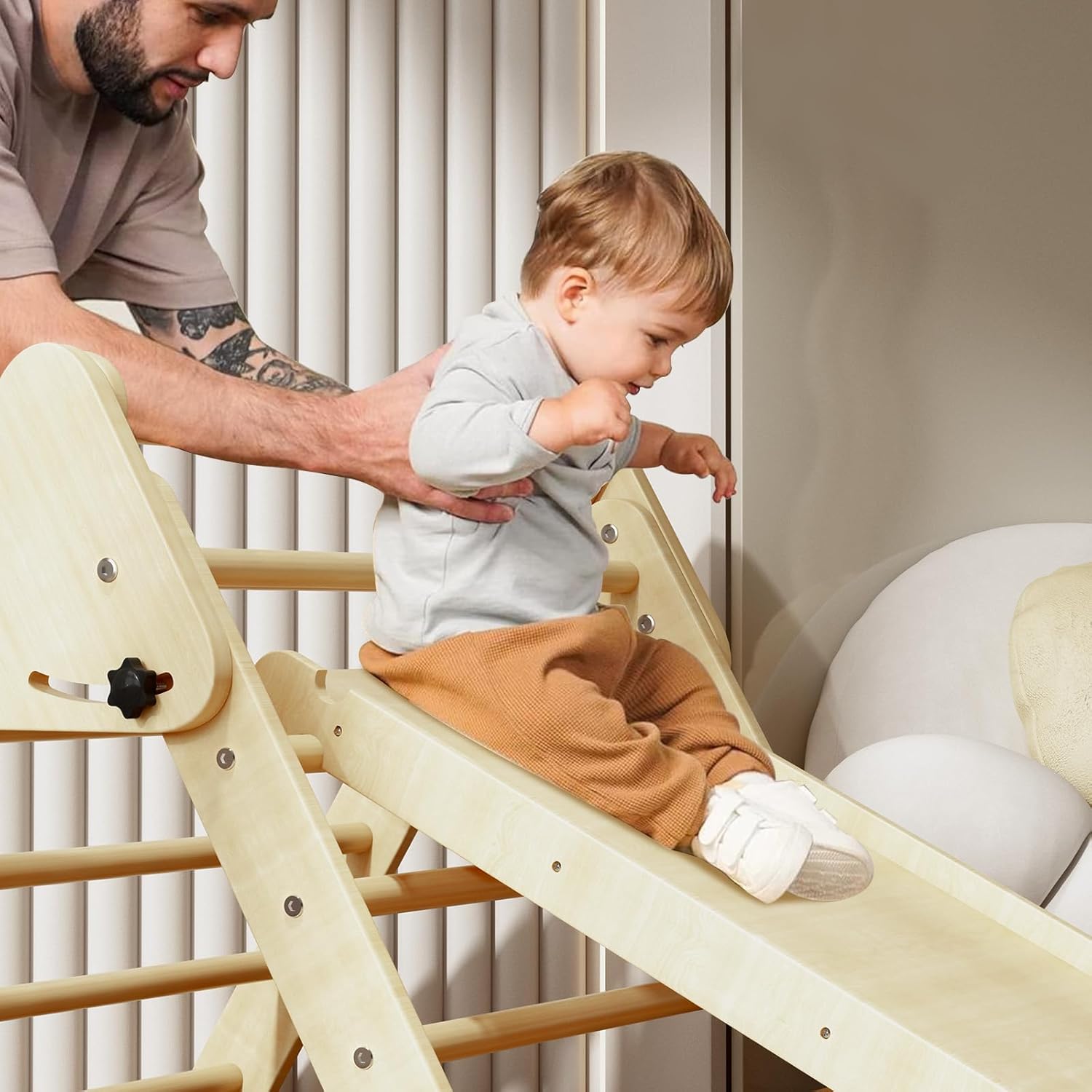 Toddler sliding down the Benarita Pikler Triangle ramp with adult assistance