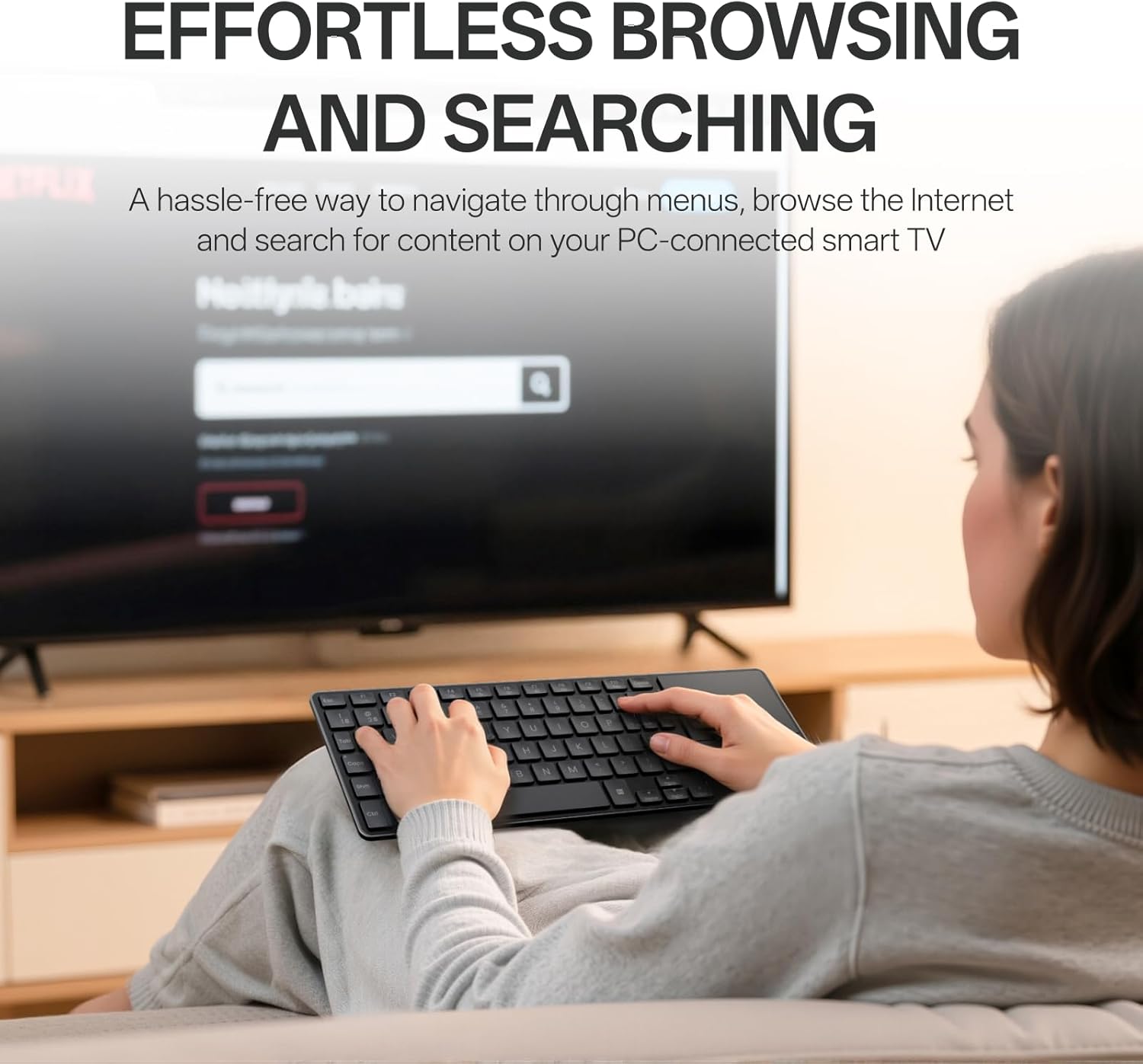 Person using Rapoo E900T keyboard to browse content on a large TV from a couch.