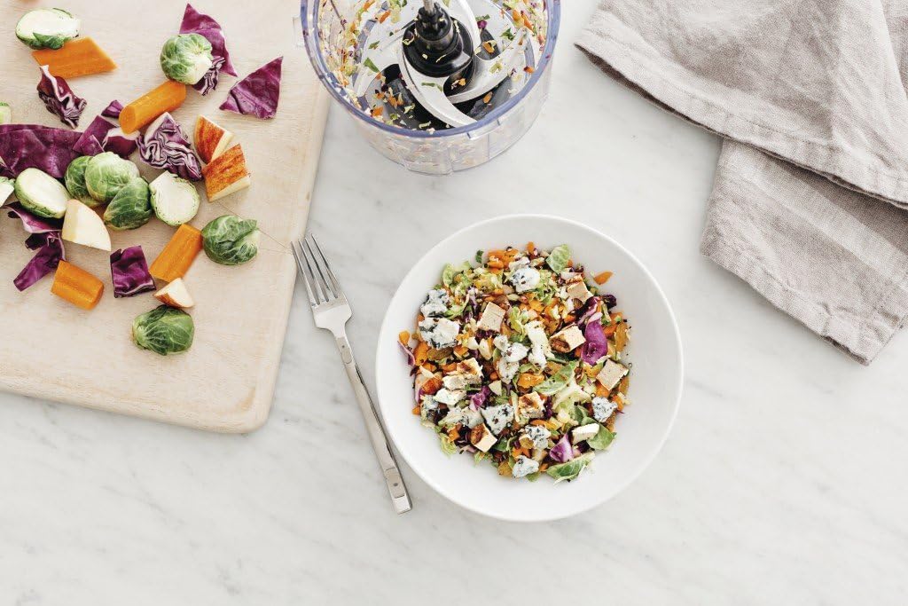A white bowl filled with finely chopped vegetables and other ingredients, with a fork resting on the side.