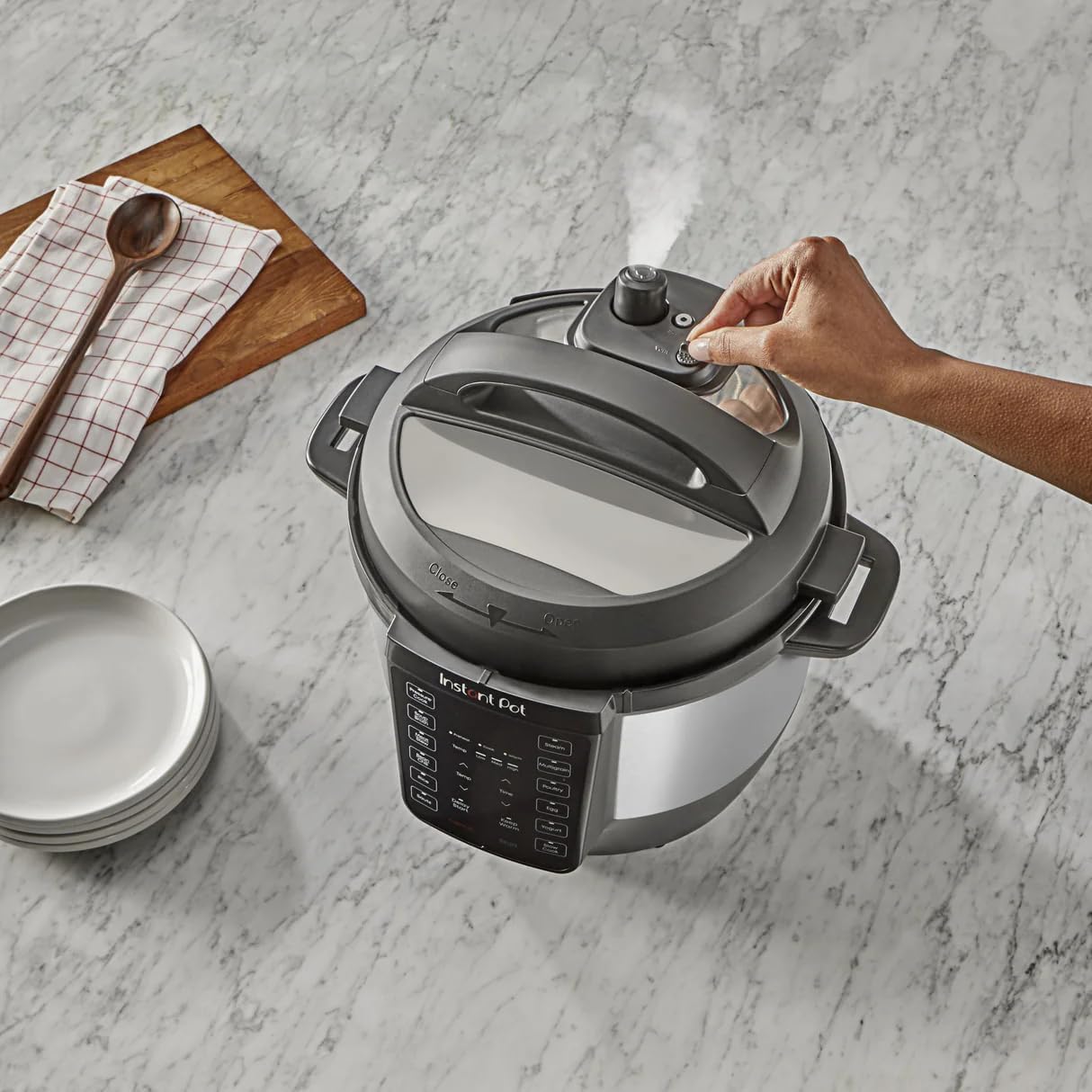 A hand turning the Easy-Release switch on the Instant-Pot RIO lid to release steam