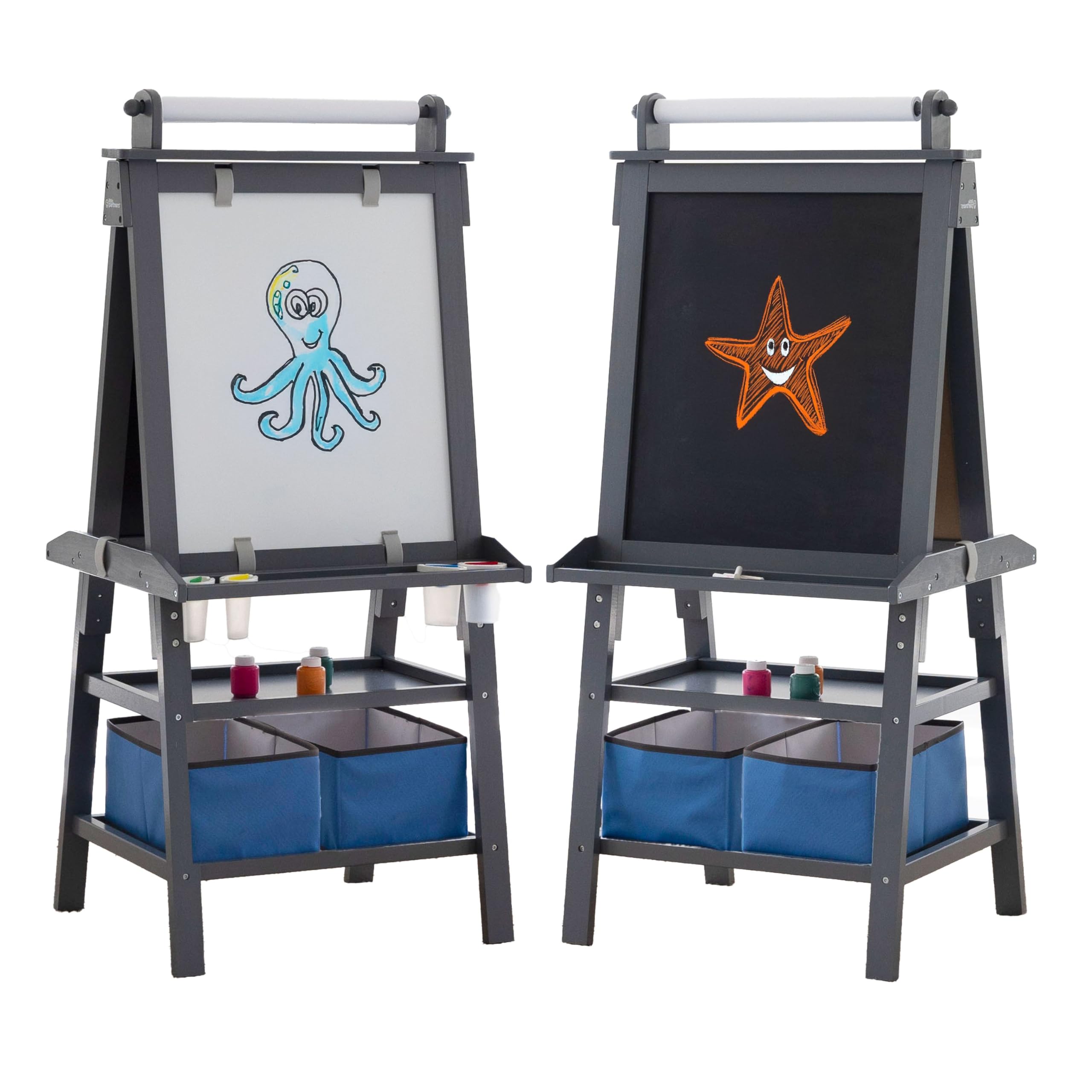 A young child stands smiling while drawing on the white magnetic dry erase side of the Little Partners Deluxe Easel.