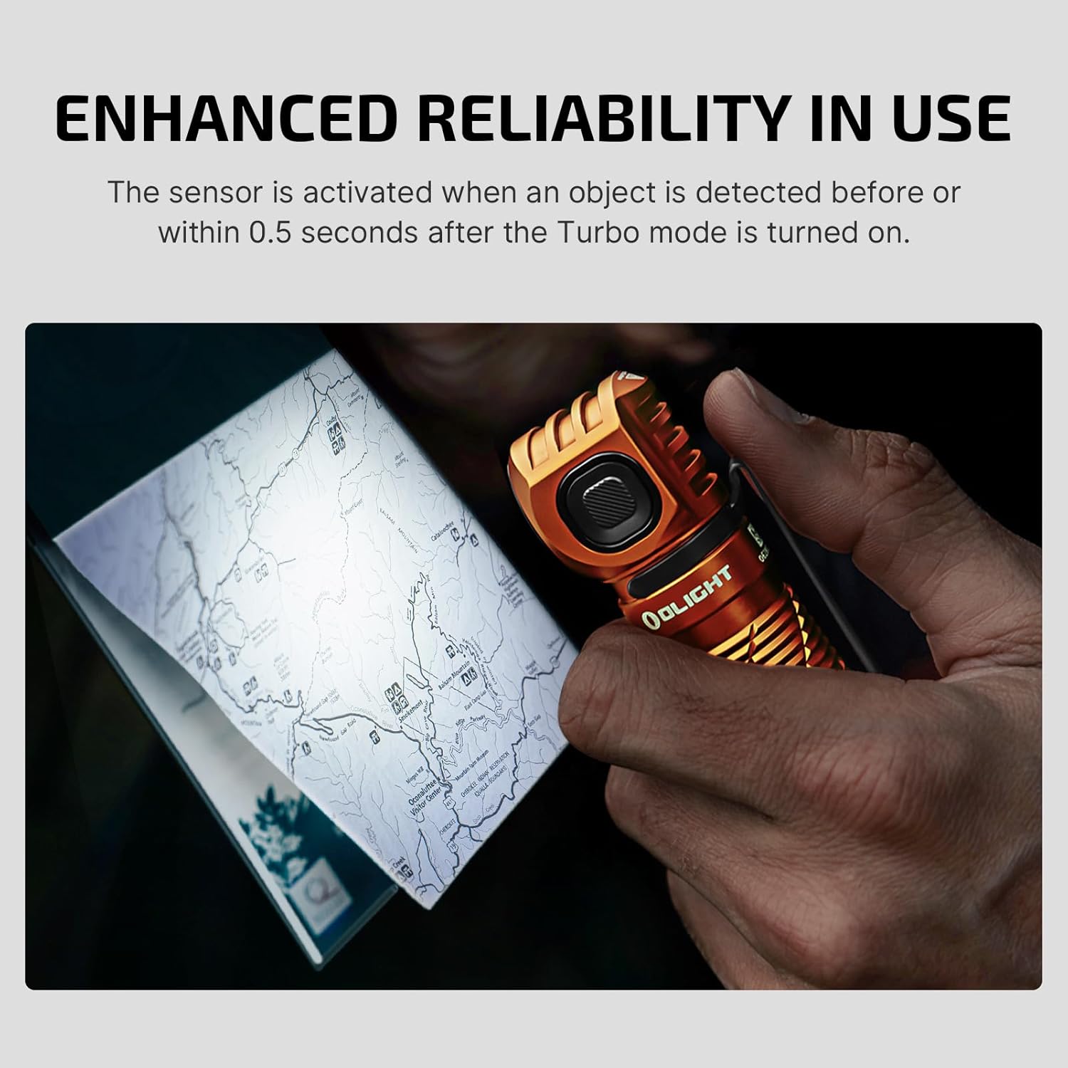 Hand holding OLIGHT Perun 3 flashlight near a map, demonstrating the proximity sensor feature.