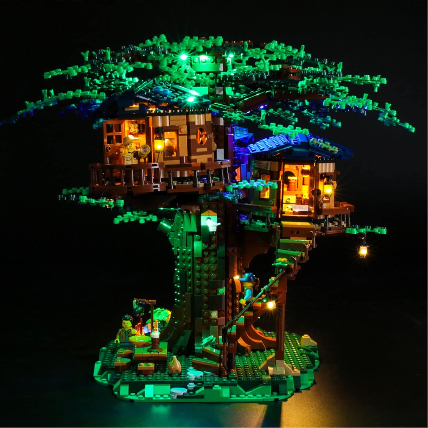 jarak dekat view of the Lego Tree House with warm yellow lights illuminating the interior of the tree houses and green lights on the tree foliage.