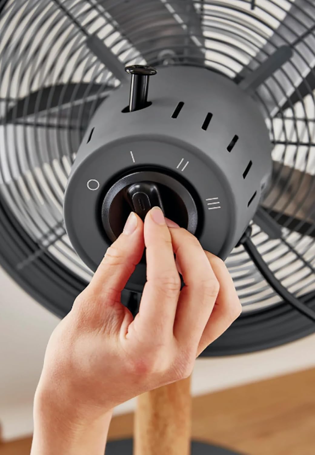 Hand adjusting the fan's rotary speed switch