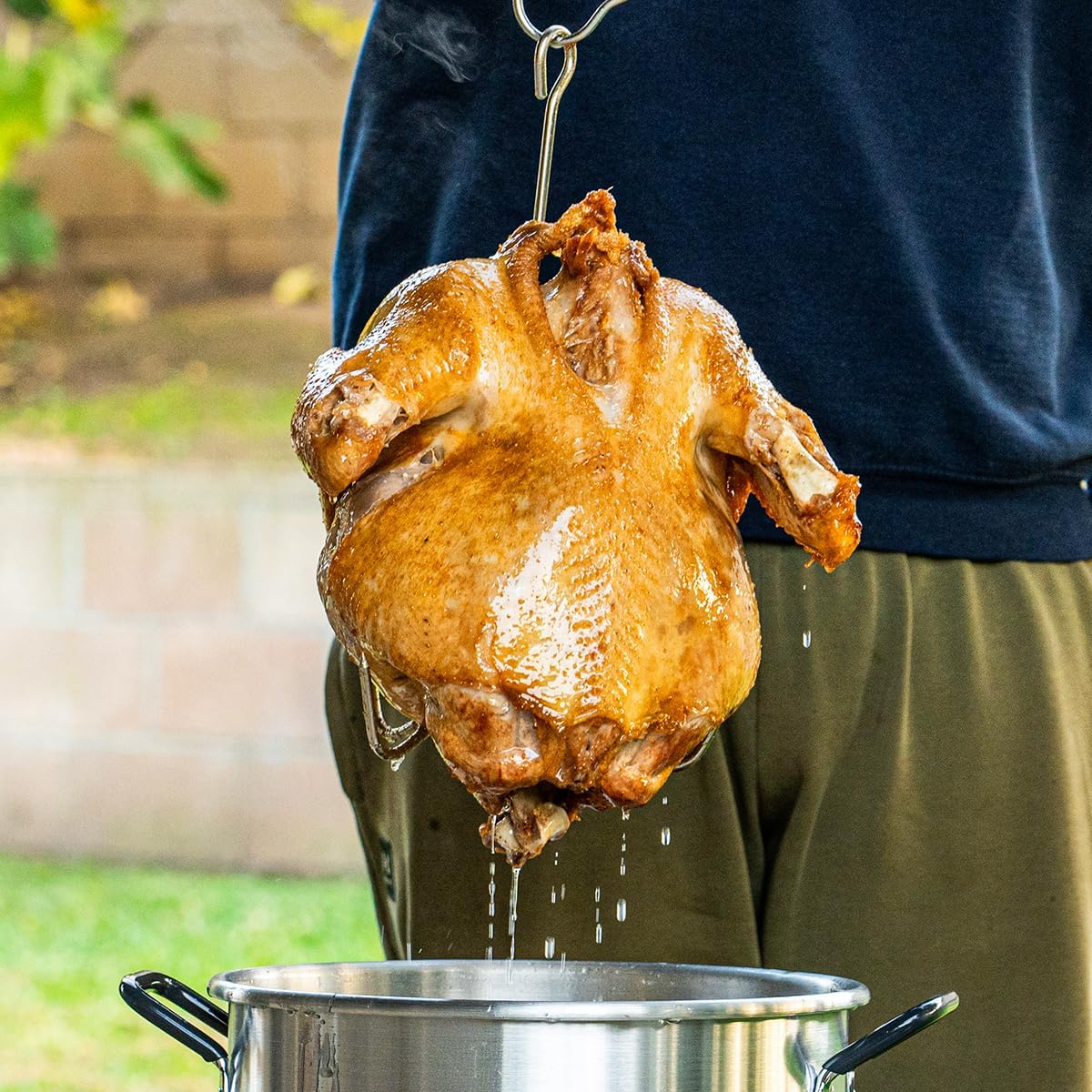 Fried turkey being lifted from the pot with a lifting hook
