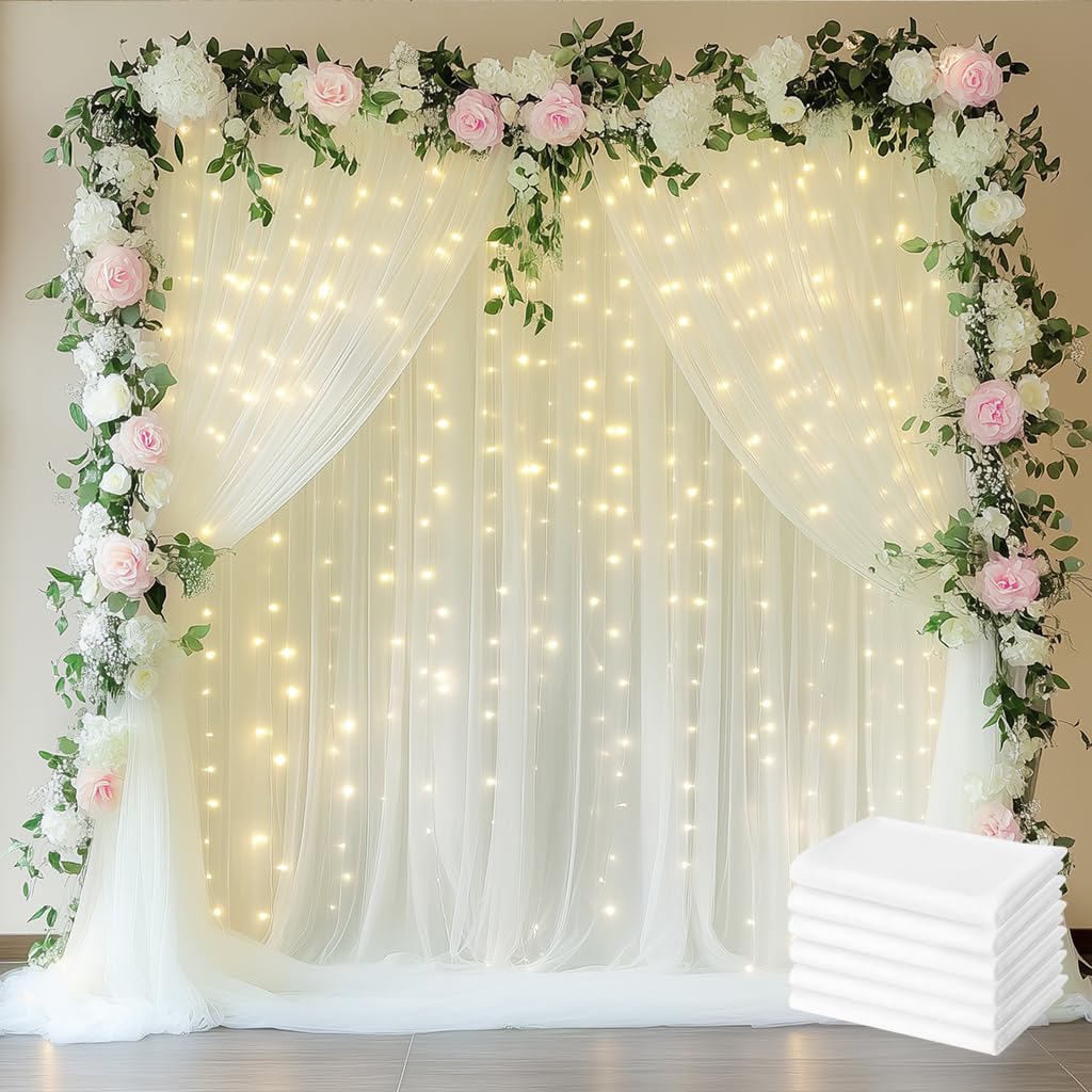 Rideaux en tulle ivoire fluides et guirlandes lumineuses pour arche de mariage elegante