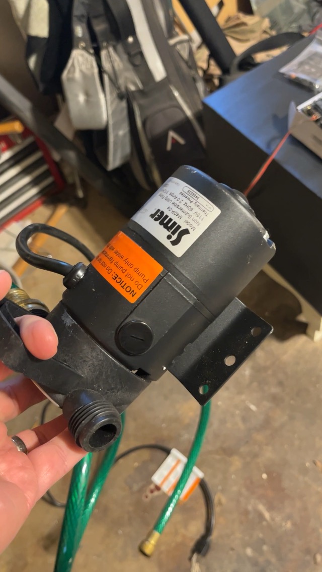 Nga afër view of the Simer M40P utility pump showing intake and discharge ports with connected hoses.