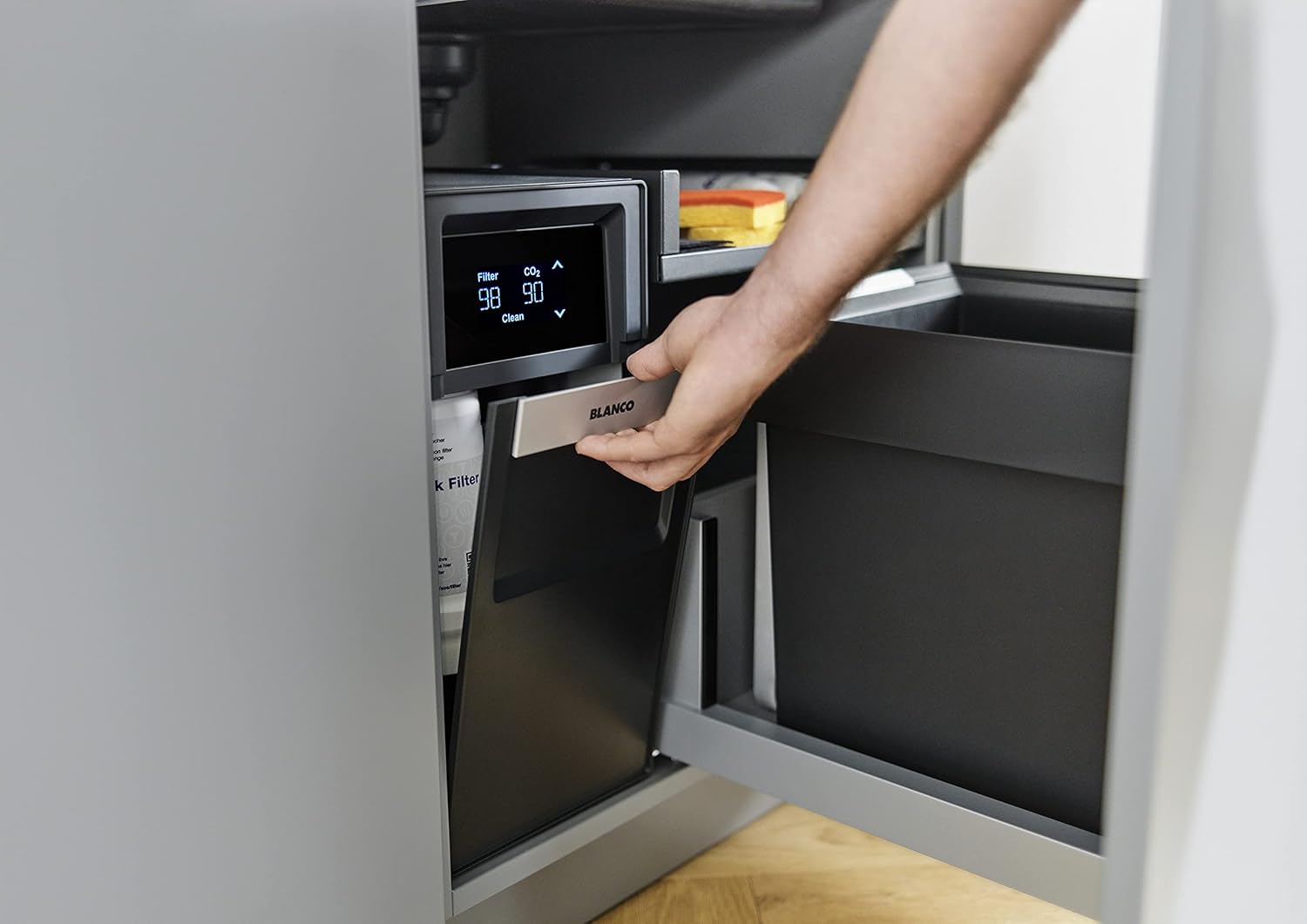 Hand accessing BLANCO drink.soda unit in cabinet