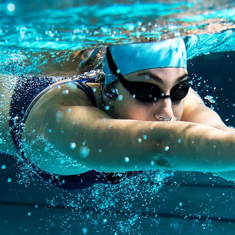 A person swimming underwater while wearing Pyle PSWP28BK headphones.