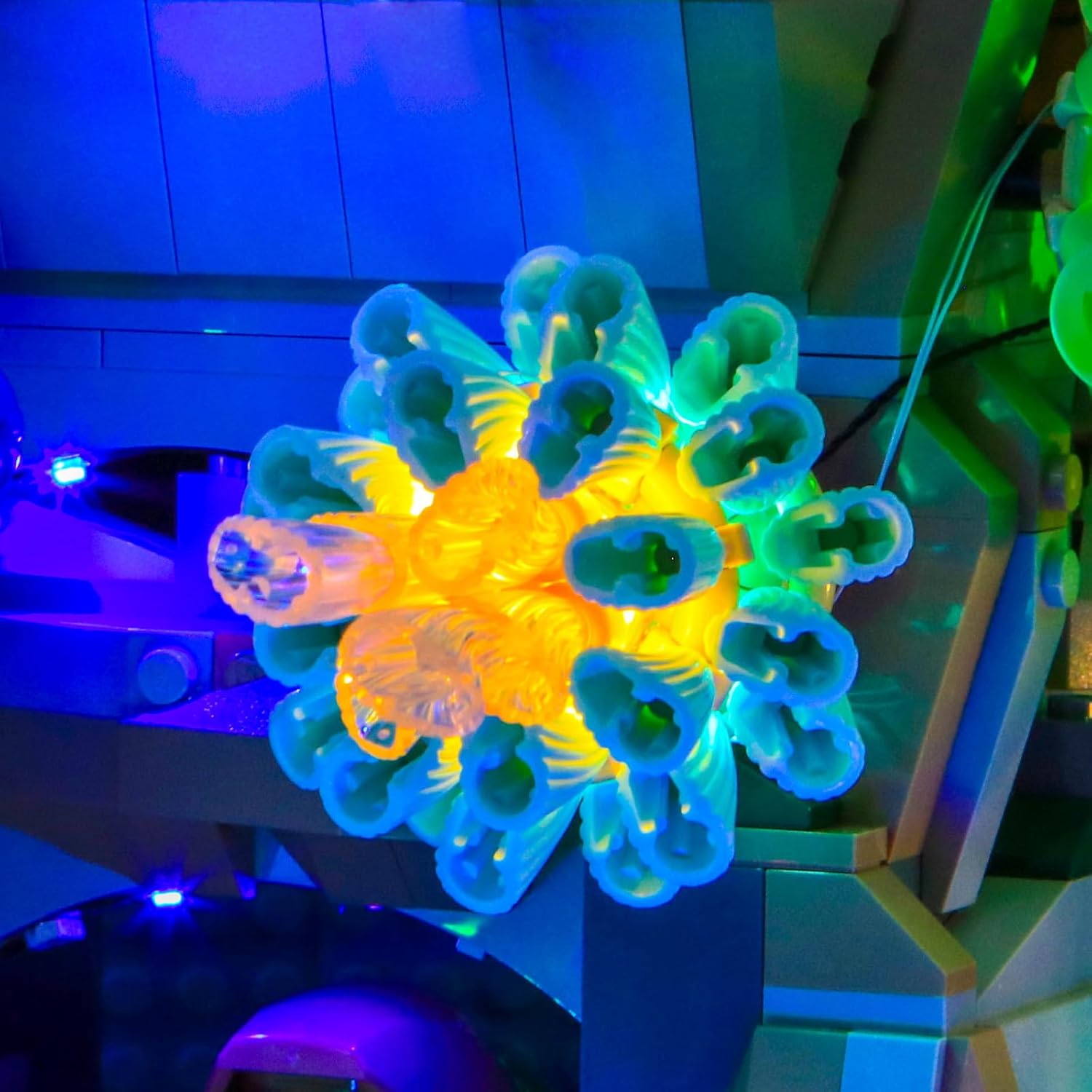 Close-up of a yellow and blue coral piece within the LEGO aquarium, illuminated by the LED kit.