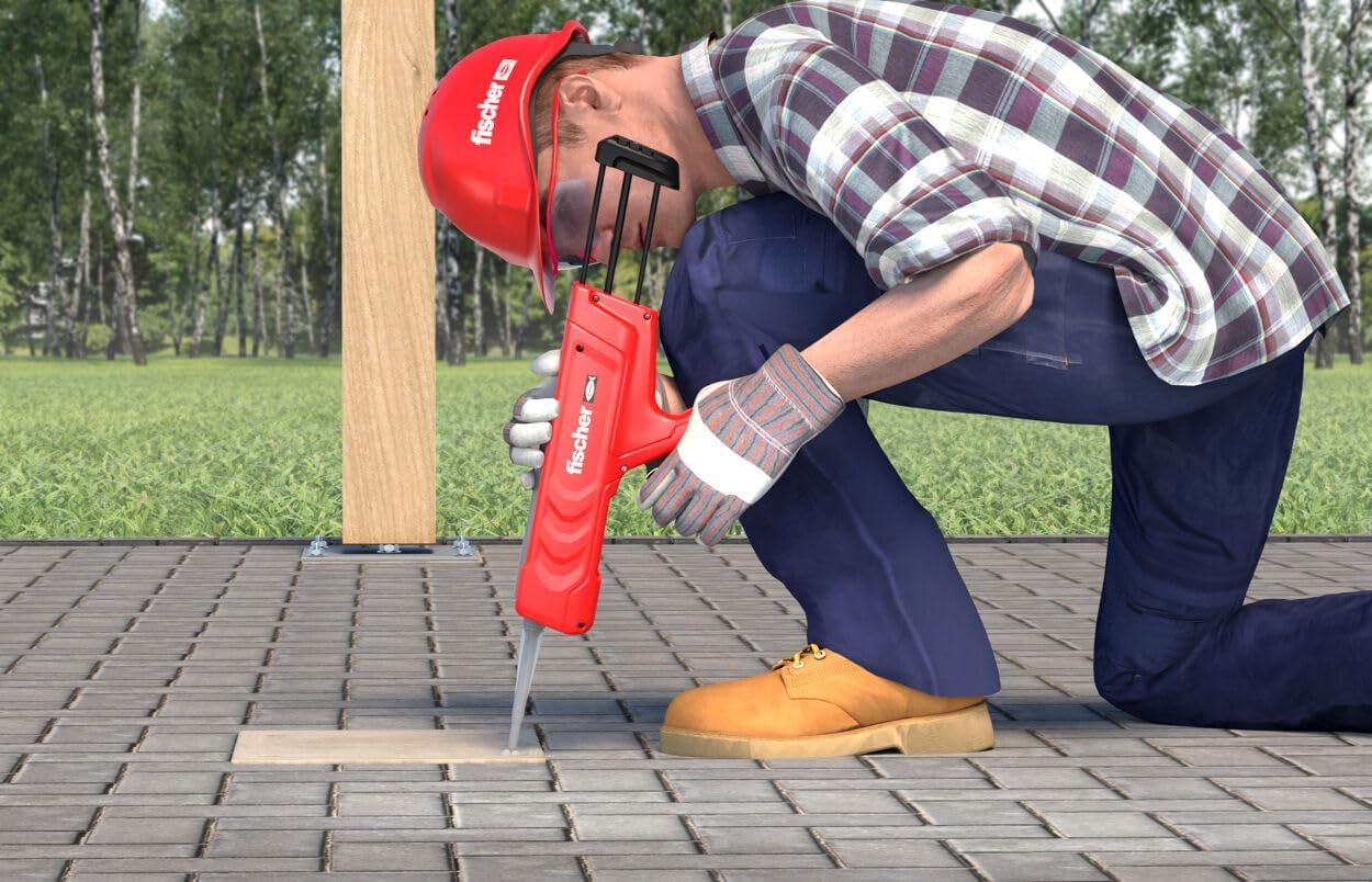 Worker using the Fischer manual dispenser to inject chemical mortar into a borehole on a paved surface