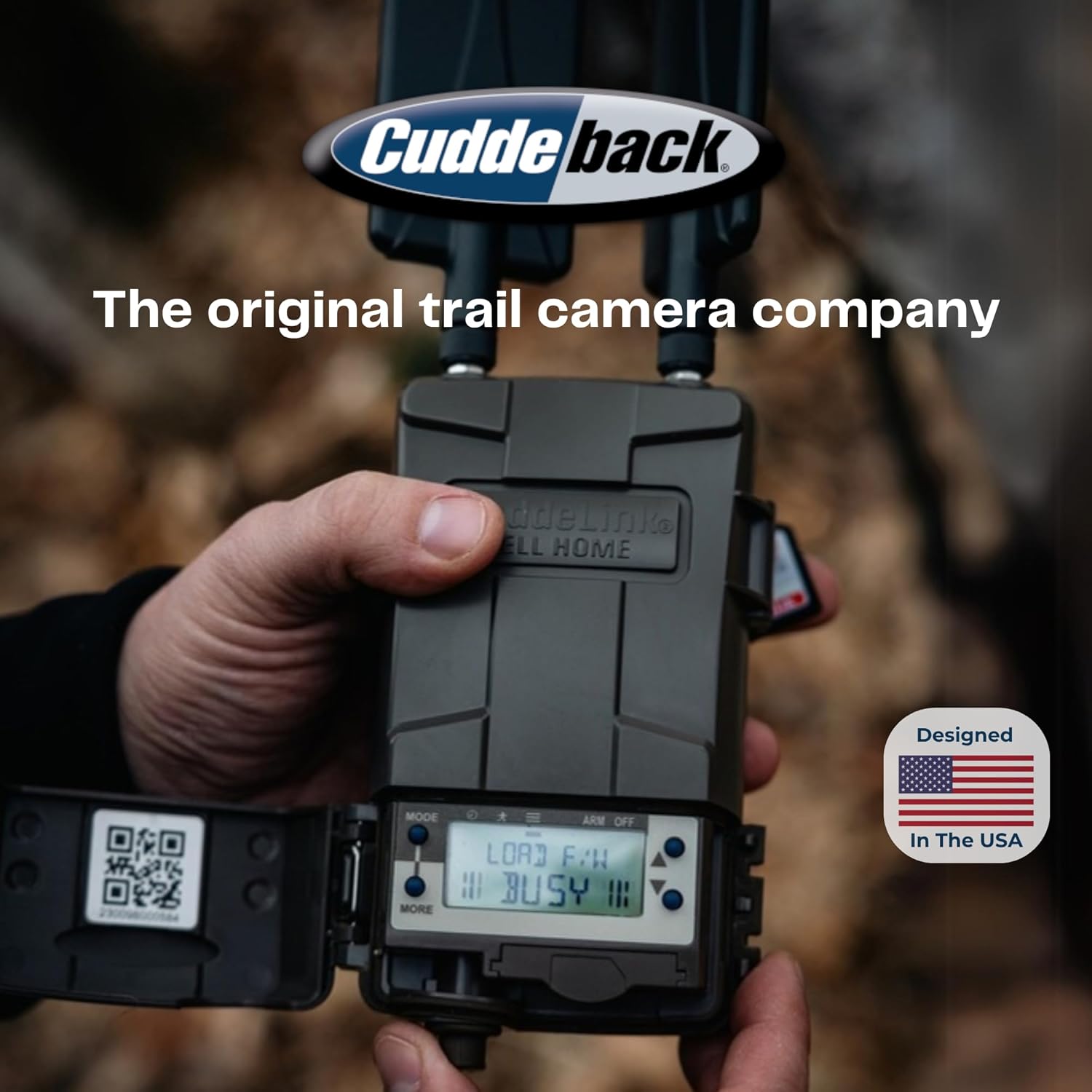 A hand holding a Cuddeback trail camera, with the Cuddeback logo and 'Designed In The USA' badge visible.