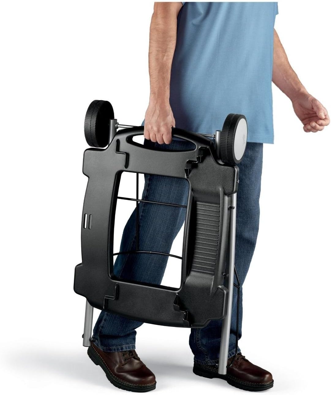 Person carrying the folded Weber Q Rolling Cart for compact storage.