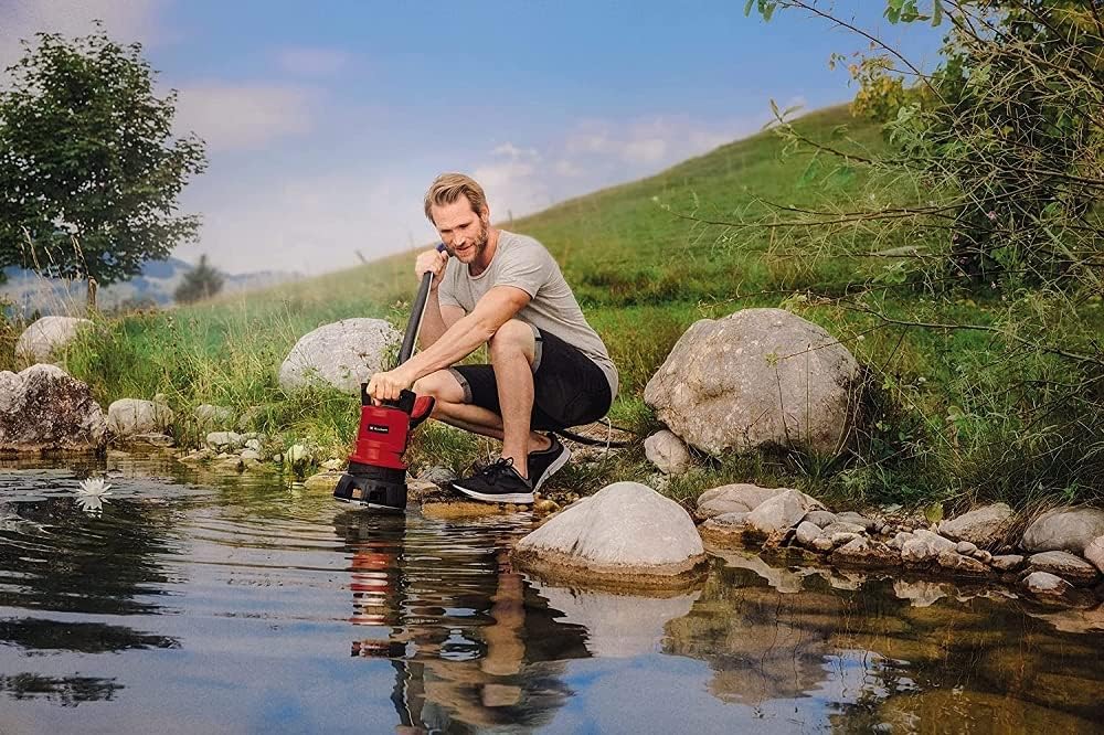 Man using Einhell GE-DP 5220 LL ECO pump to drain water from a pond.