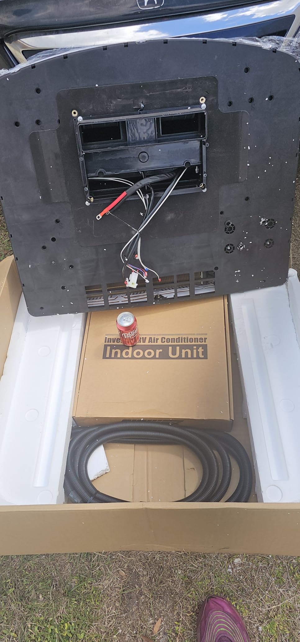 OutEquip black 12V AC installed on truck camper roof surrounded by solar panels on both sides, with trees in background