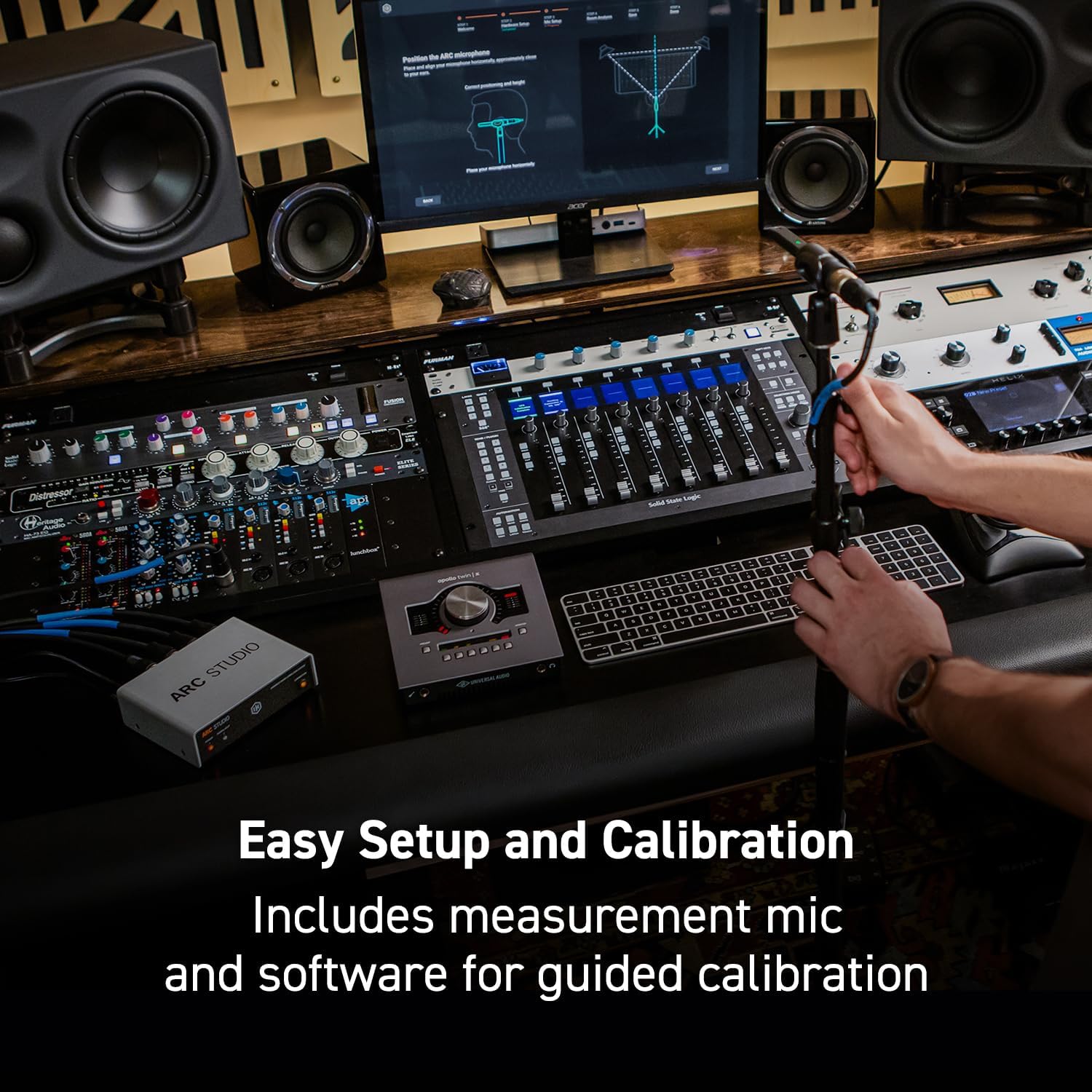 Person setting up the ARC measurement microphone on a stand in a studio environment, with a laptop displaying the ARC 4 software