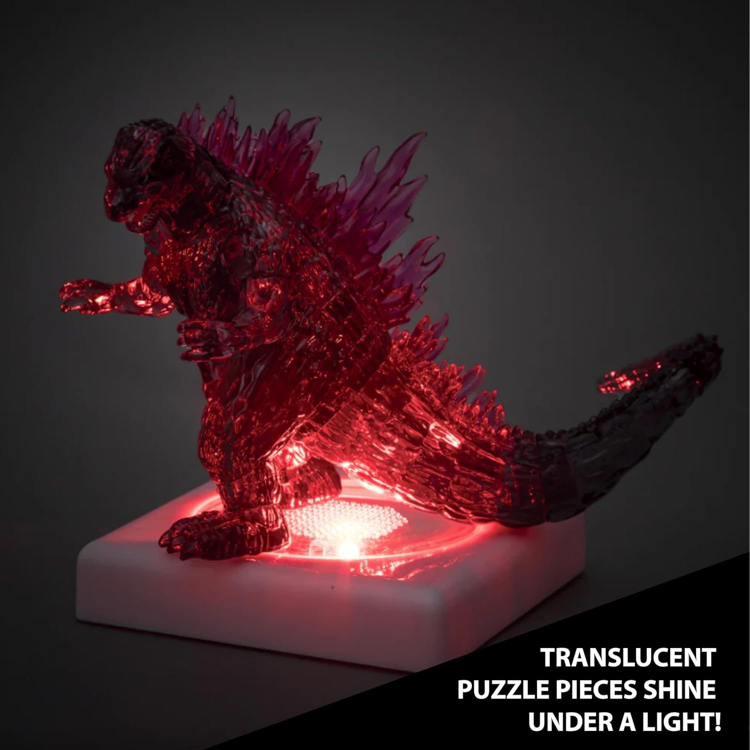 Completed Bepuzzled Godzilla Ultra Deluxe 3D Crystal Puzzle glowing red on a light-up base in a dark room.