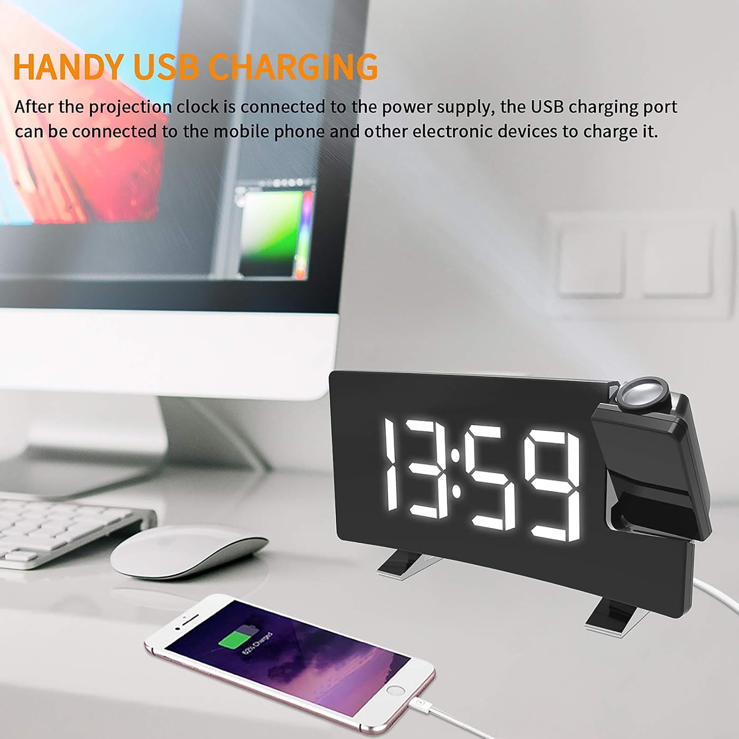 Image showing a smartphone connected to the USB charging port on the YUNYODA Digital Projection Alarm Clock, which is placed on a desk next to a computer monitor.