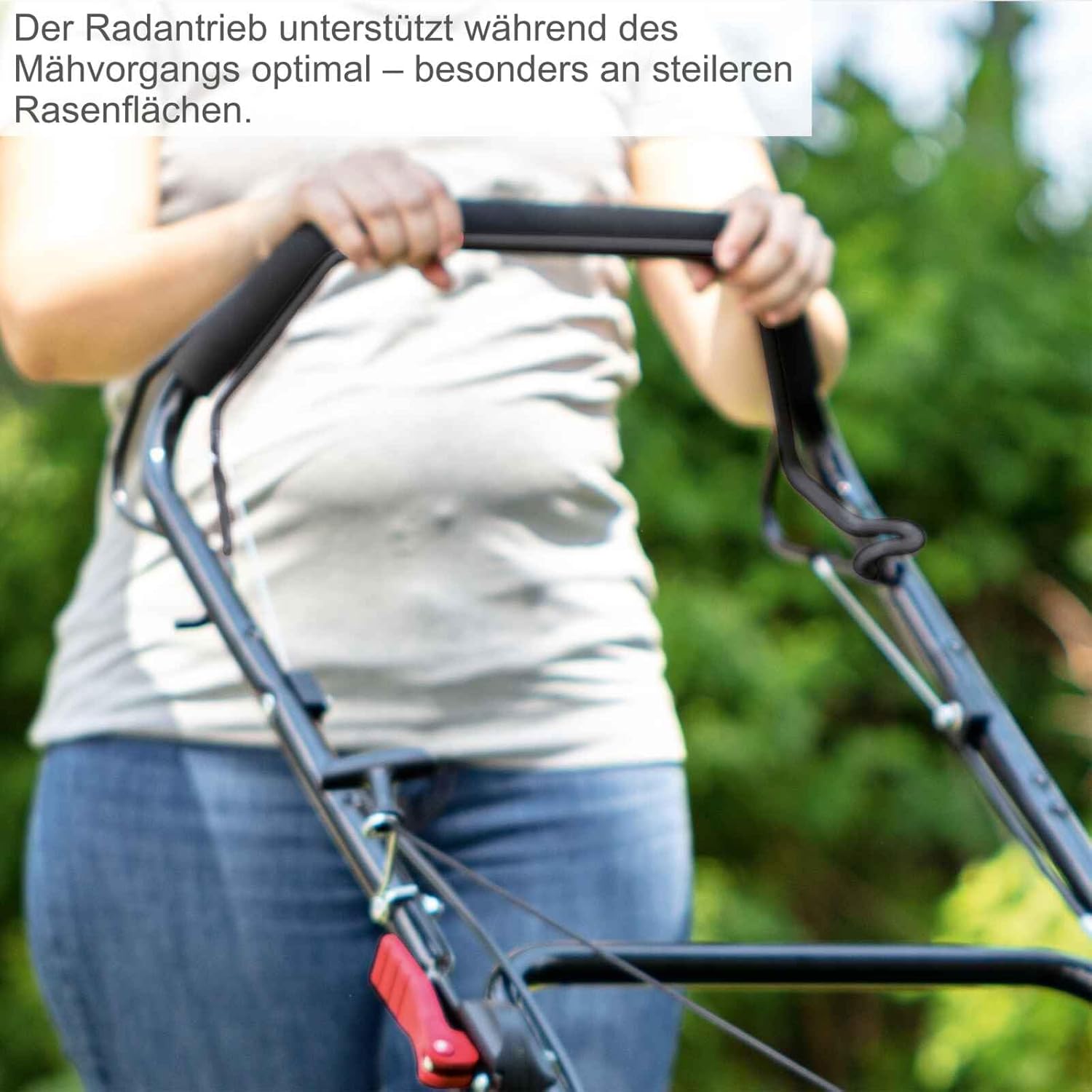 Close-up of a person operating the lawnmower, highlighting the self-propelled drive system.