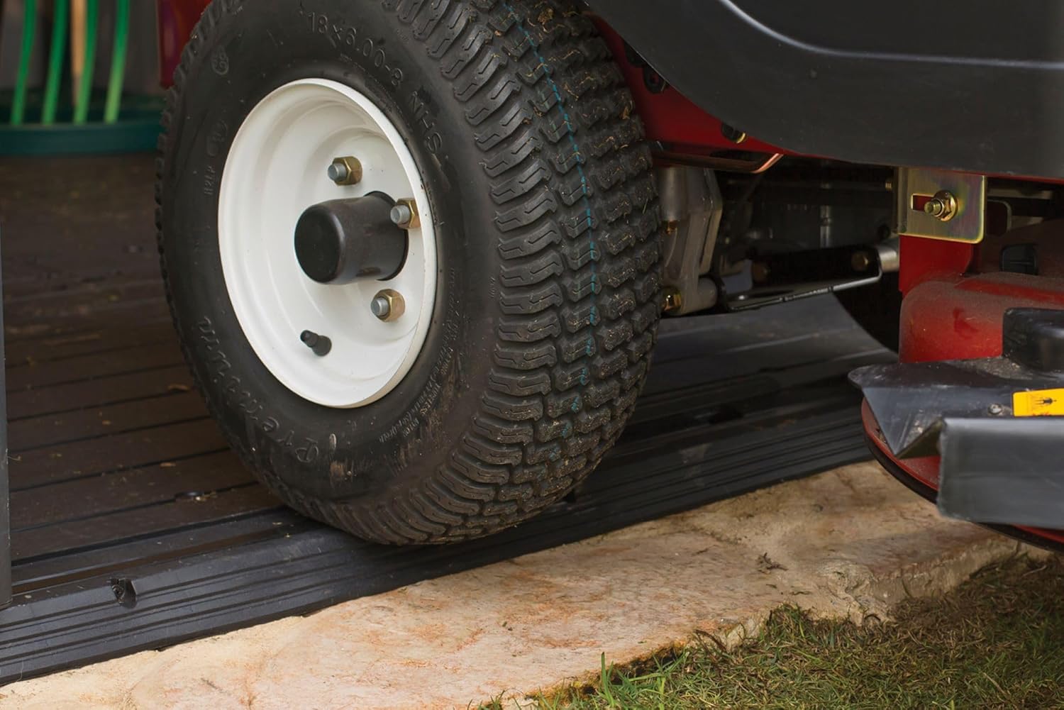 A lawnmower being rolled into the shed, demonstrating the wide door entry.