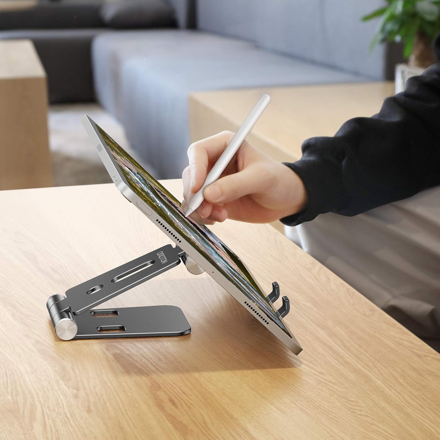 A person using a tablet placed on the Omoton C4 stand, demonstrating its use for drawing or typing.