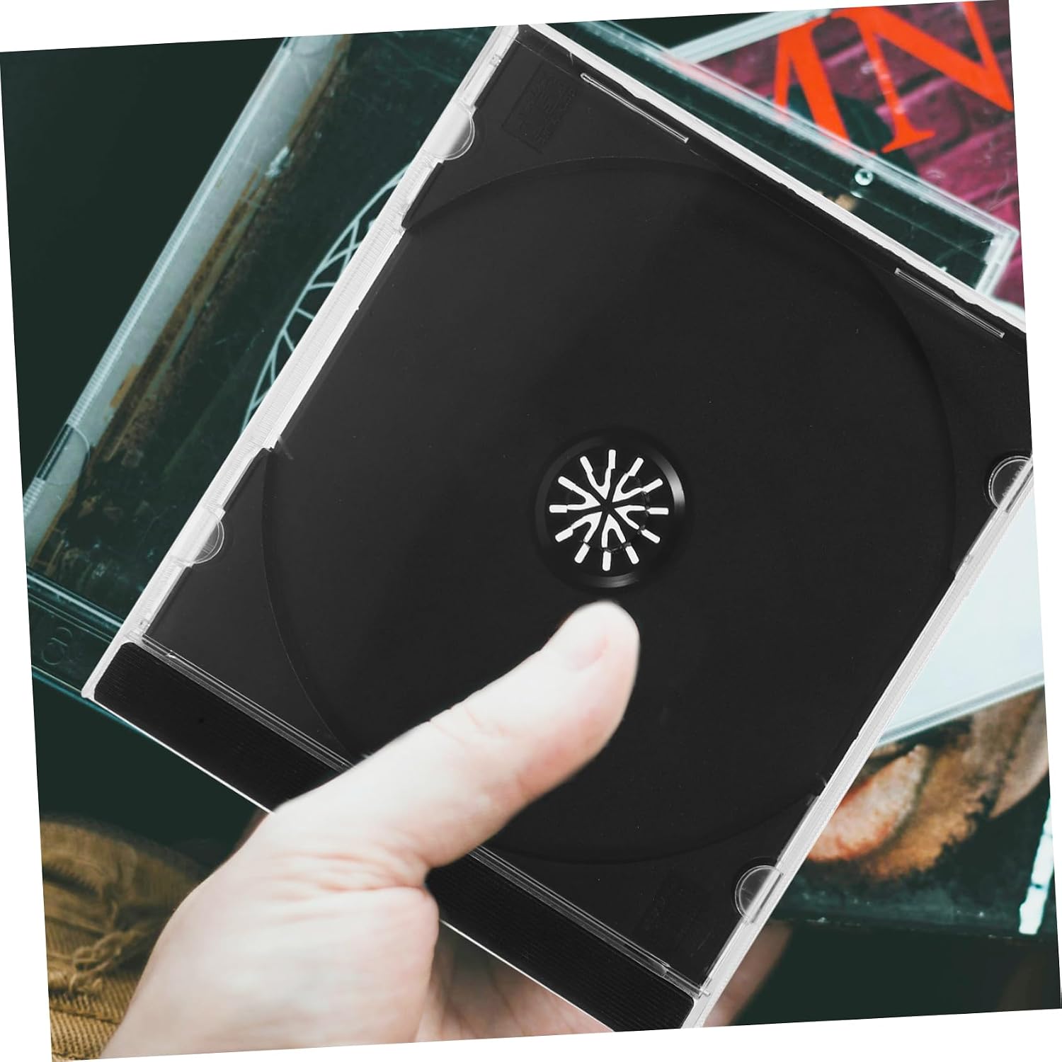 A hand holding a black CD/DVD clam shell case, demonstrating its portability
