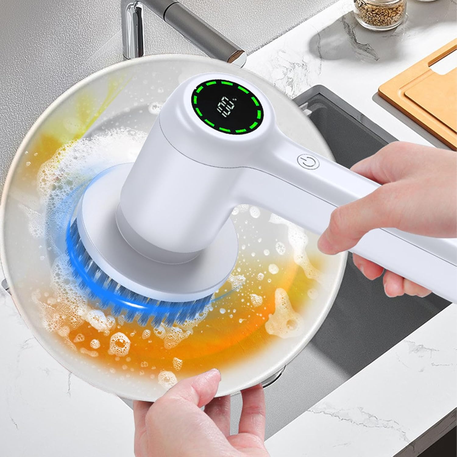 Hand holding the electric cleaning brush, showing the digital battery display at 100% while cleaning a plate